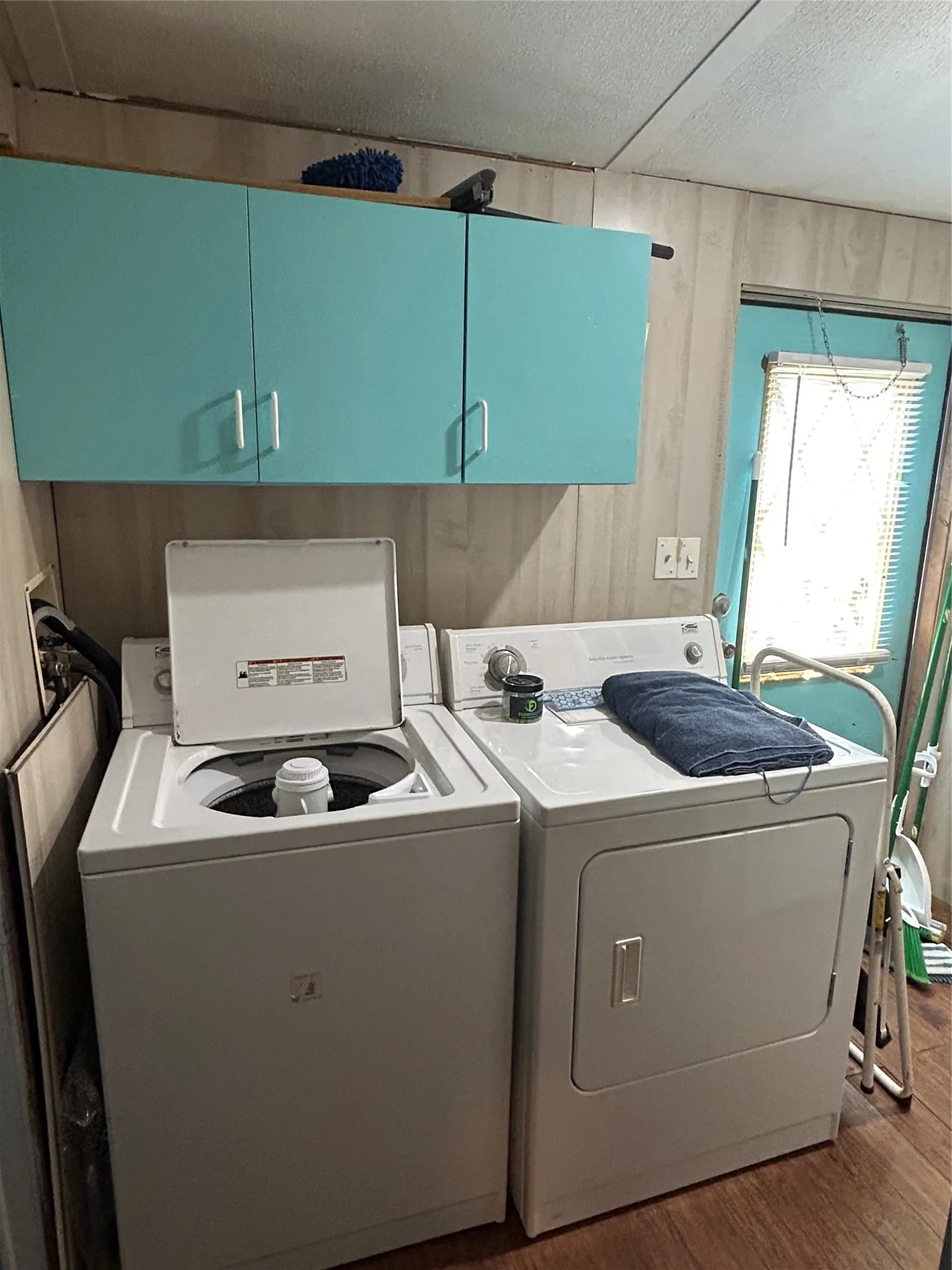 Laundry room featuring cabinet space, washing machine and clothes dryer, wood finished floors, and a textured ceiling