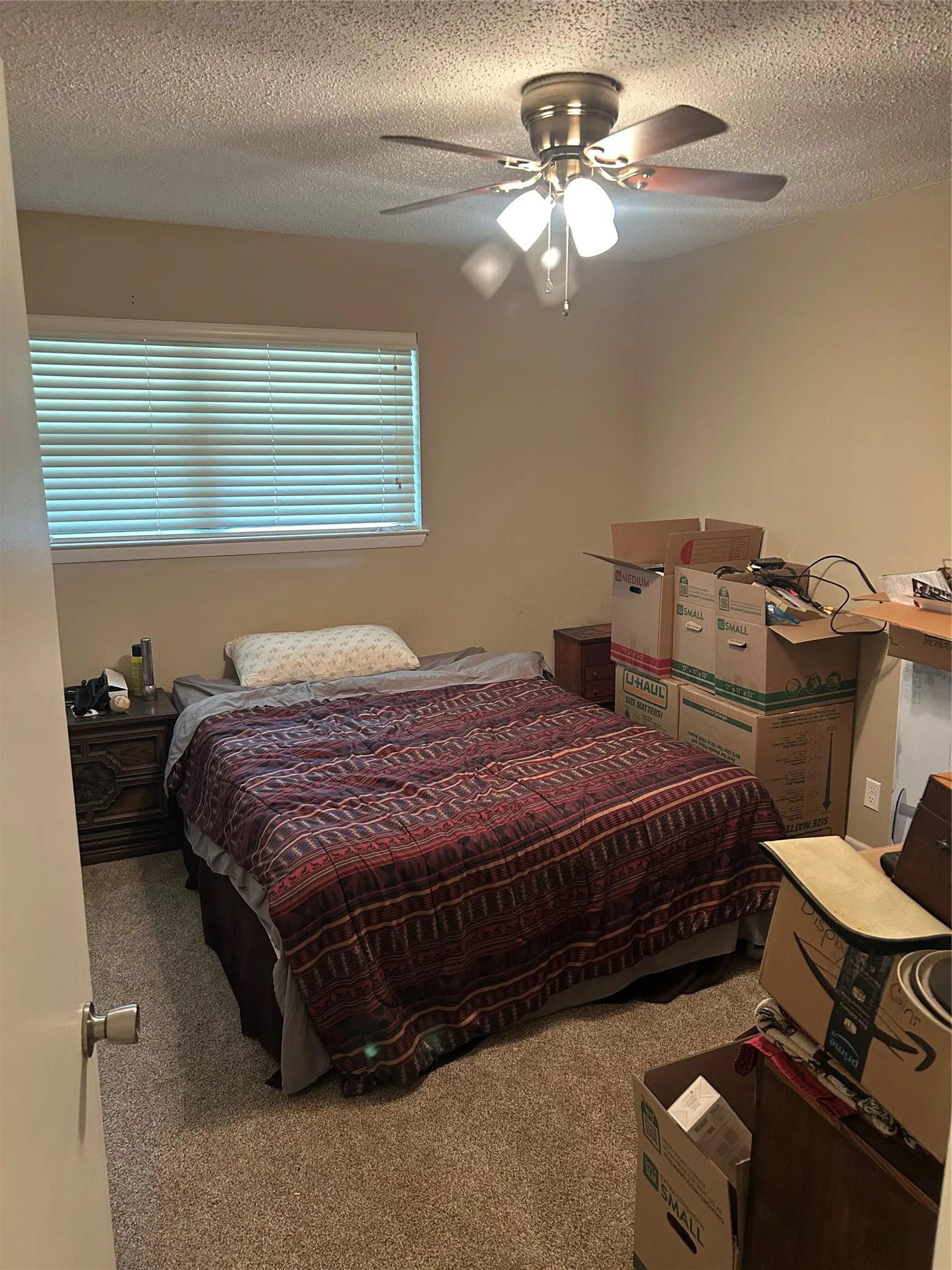 Bedroom with carpet floors, a ceiling fan, and a textured ceiling