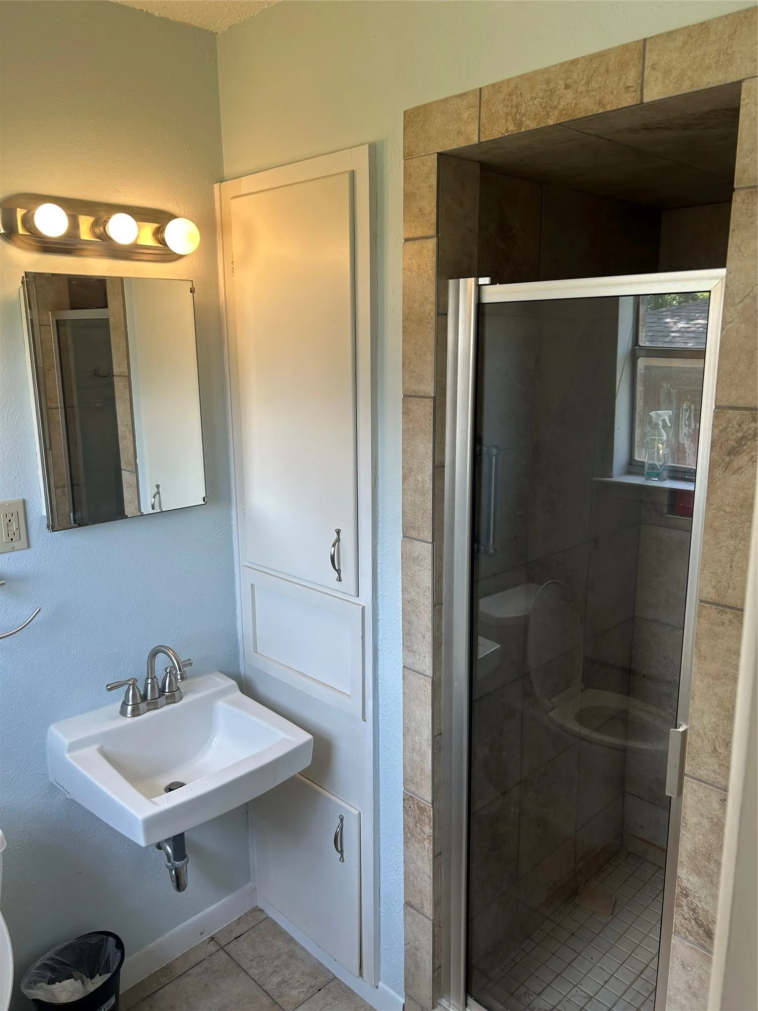 Bathroom featuring a stall shower, tile patterned floors, and a sink