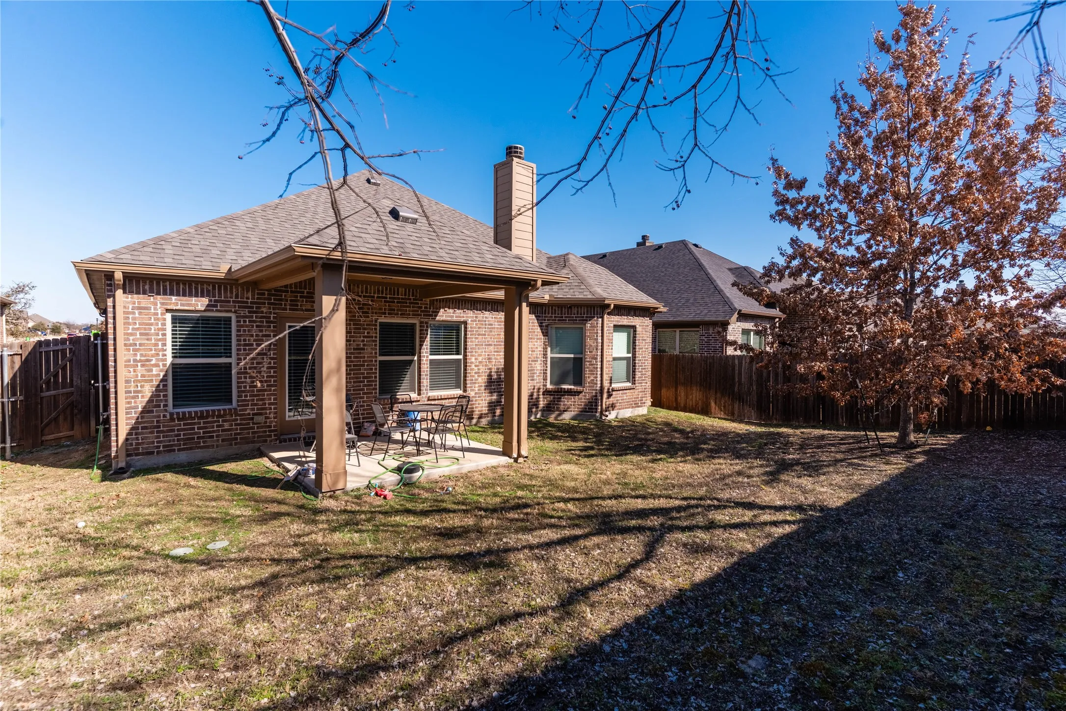 Back of property featuring a patio, brick siding, a fenced backyard, and a chimney