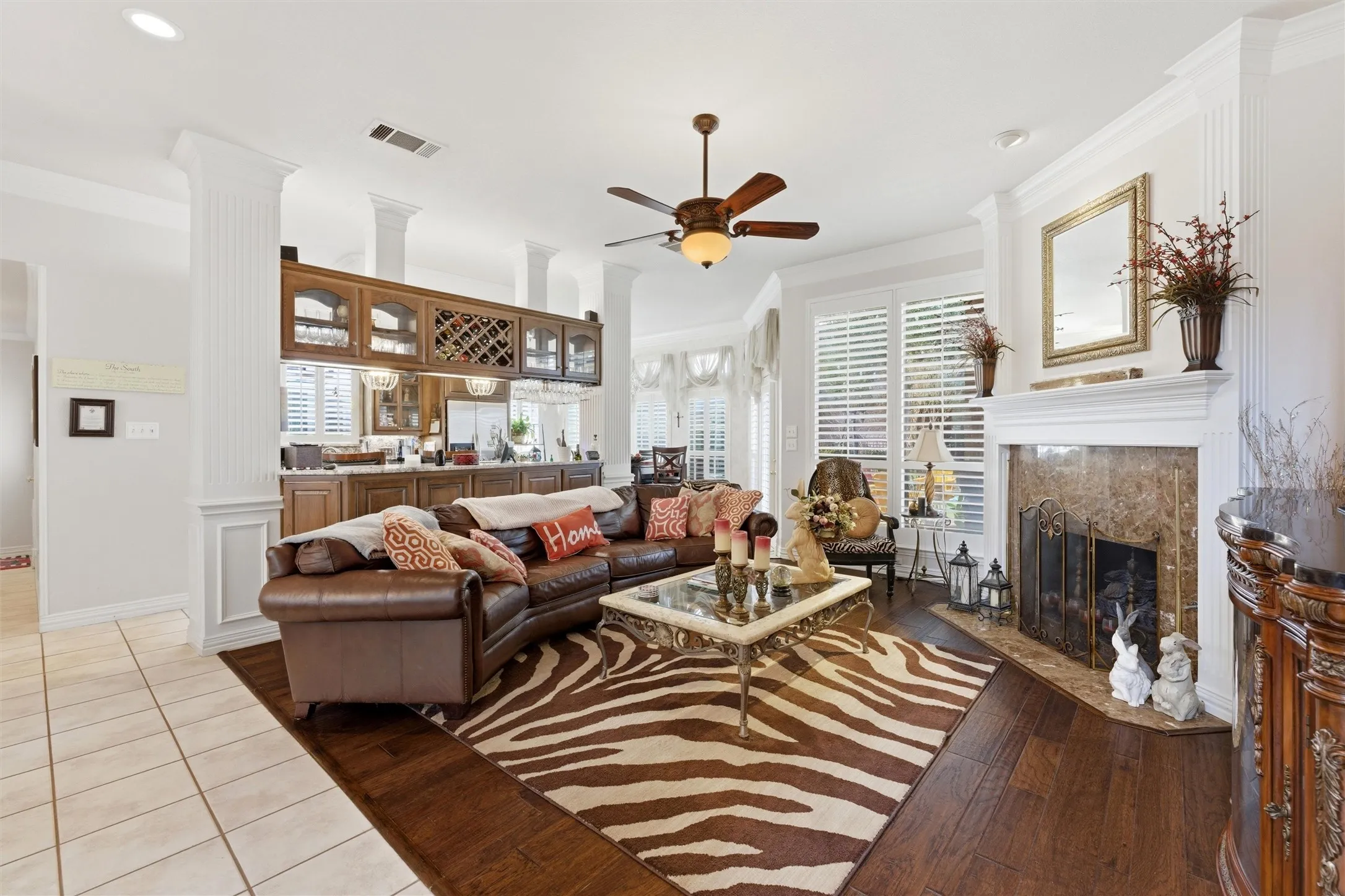 Living area with crown molding, healthy amount of natural light, decorative columns, a premium fireplace, and hardwood / wood-style flooring