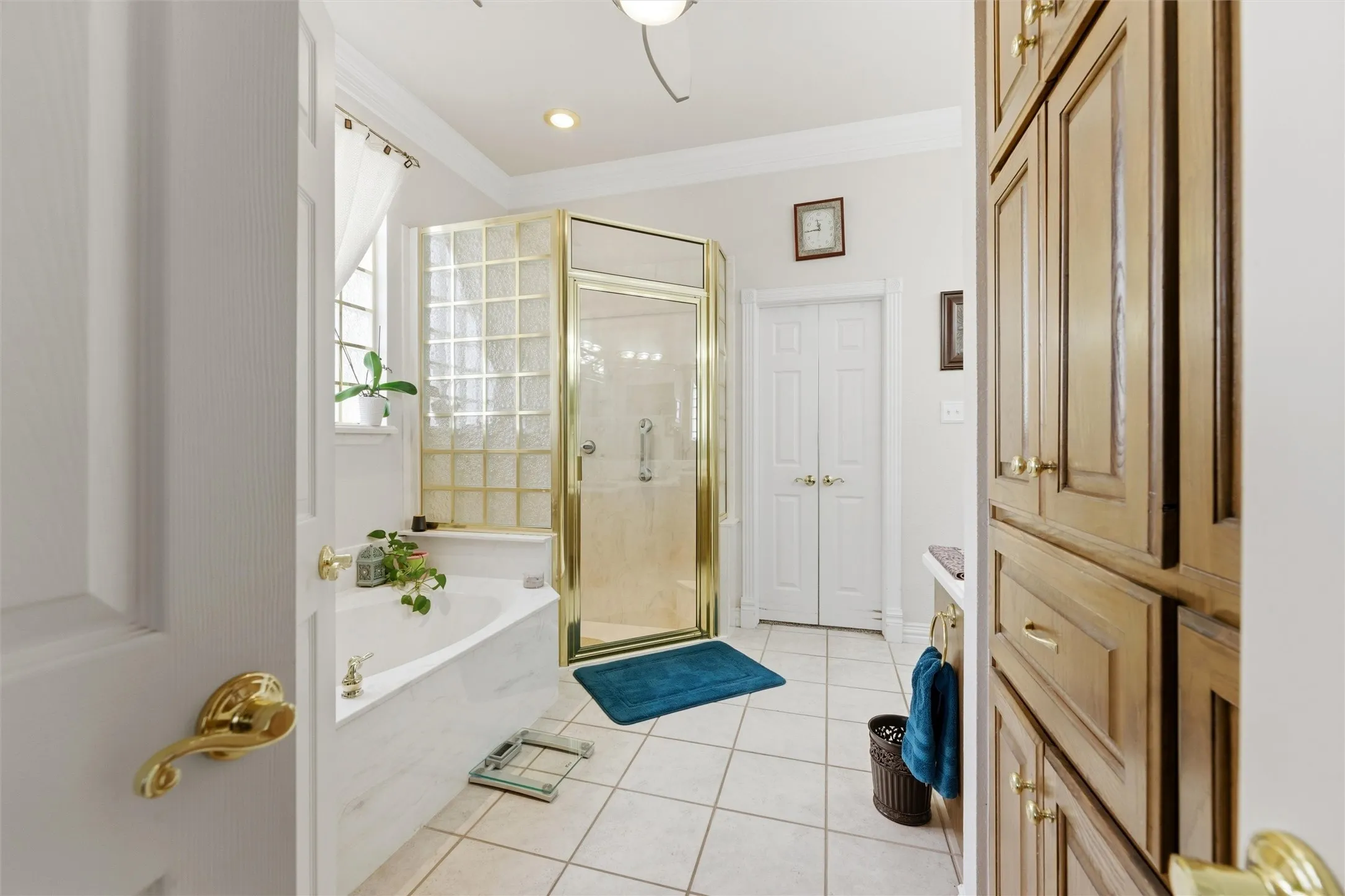 Full bathroom featuring a stall shower, light tile patterned floors, vanity, crown molding, and a bath