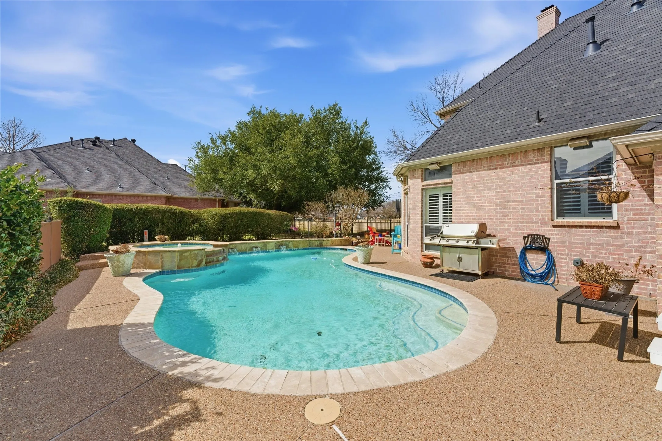 Integrated pool / spa with area for grilling, a patio area, and a fenced backyard
