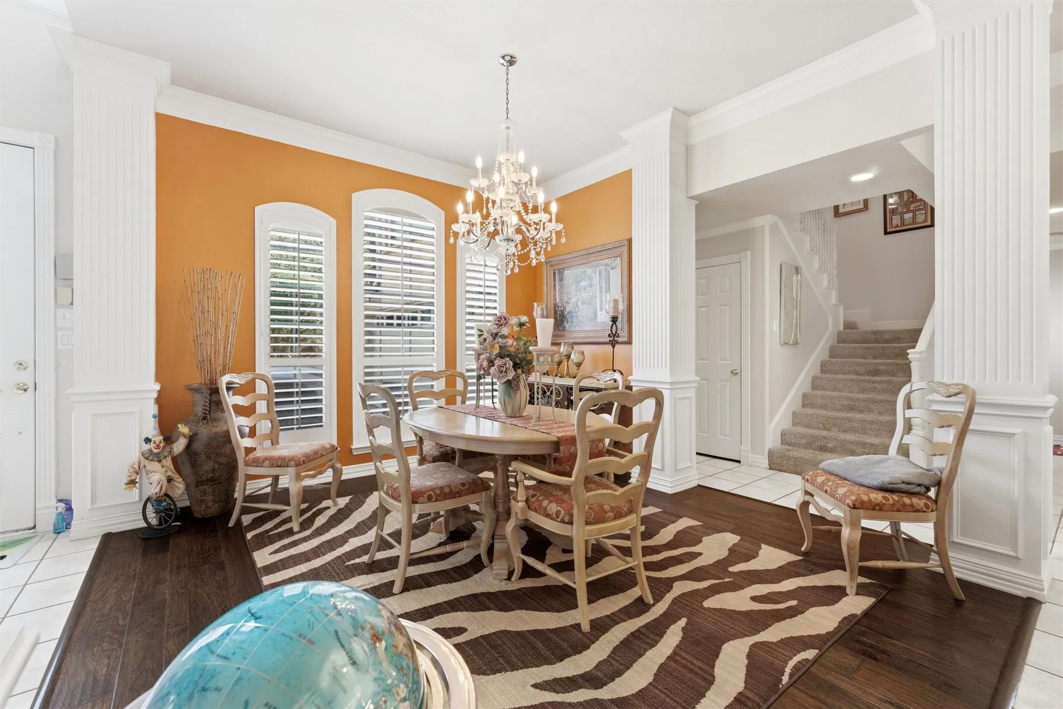 Dining space with decorative columns, crown molding, light wood finished floors, and a chandelier