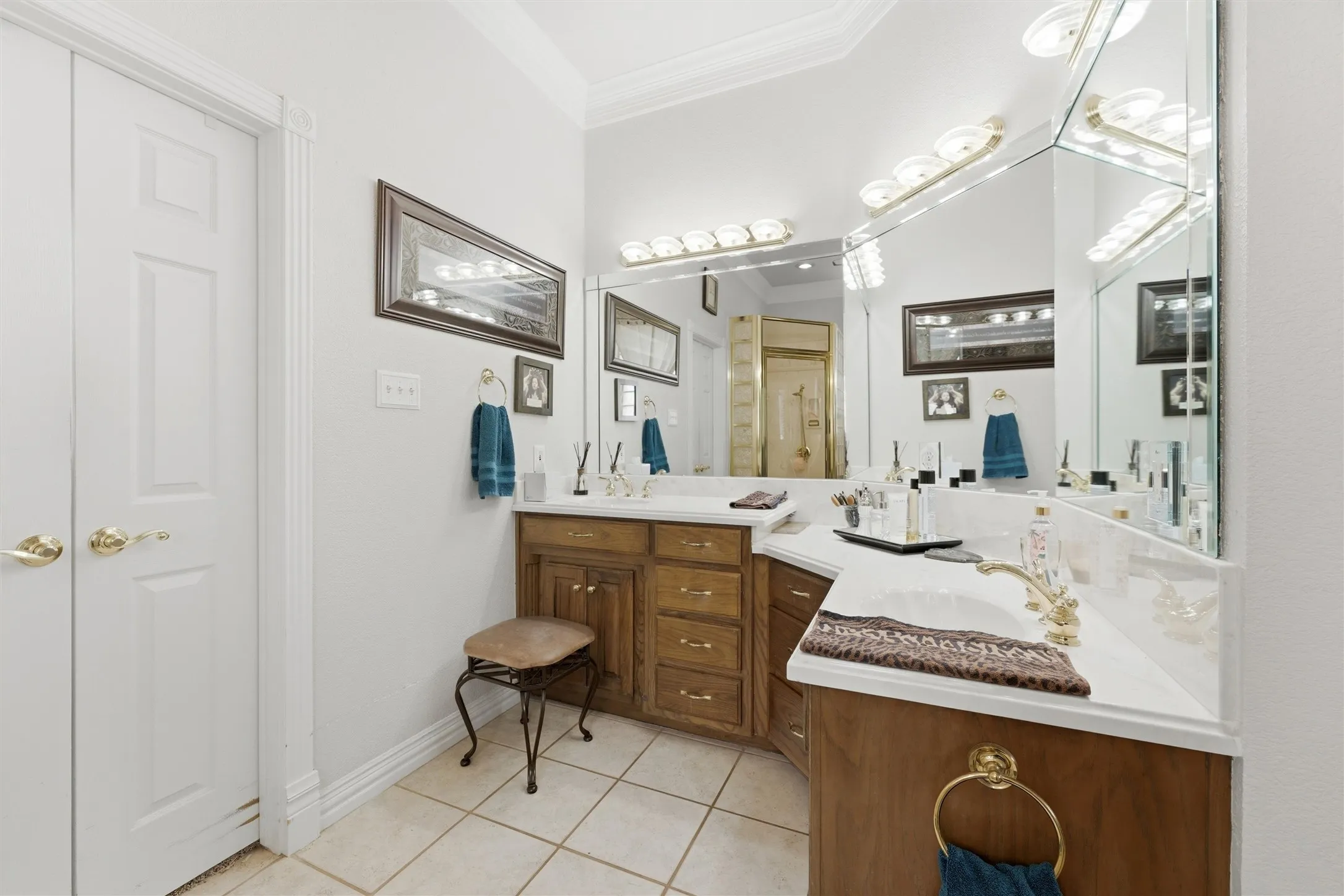Bathroom with ornamental molding, double vanity, and light tile patterned floors