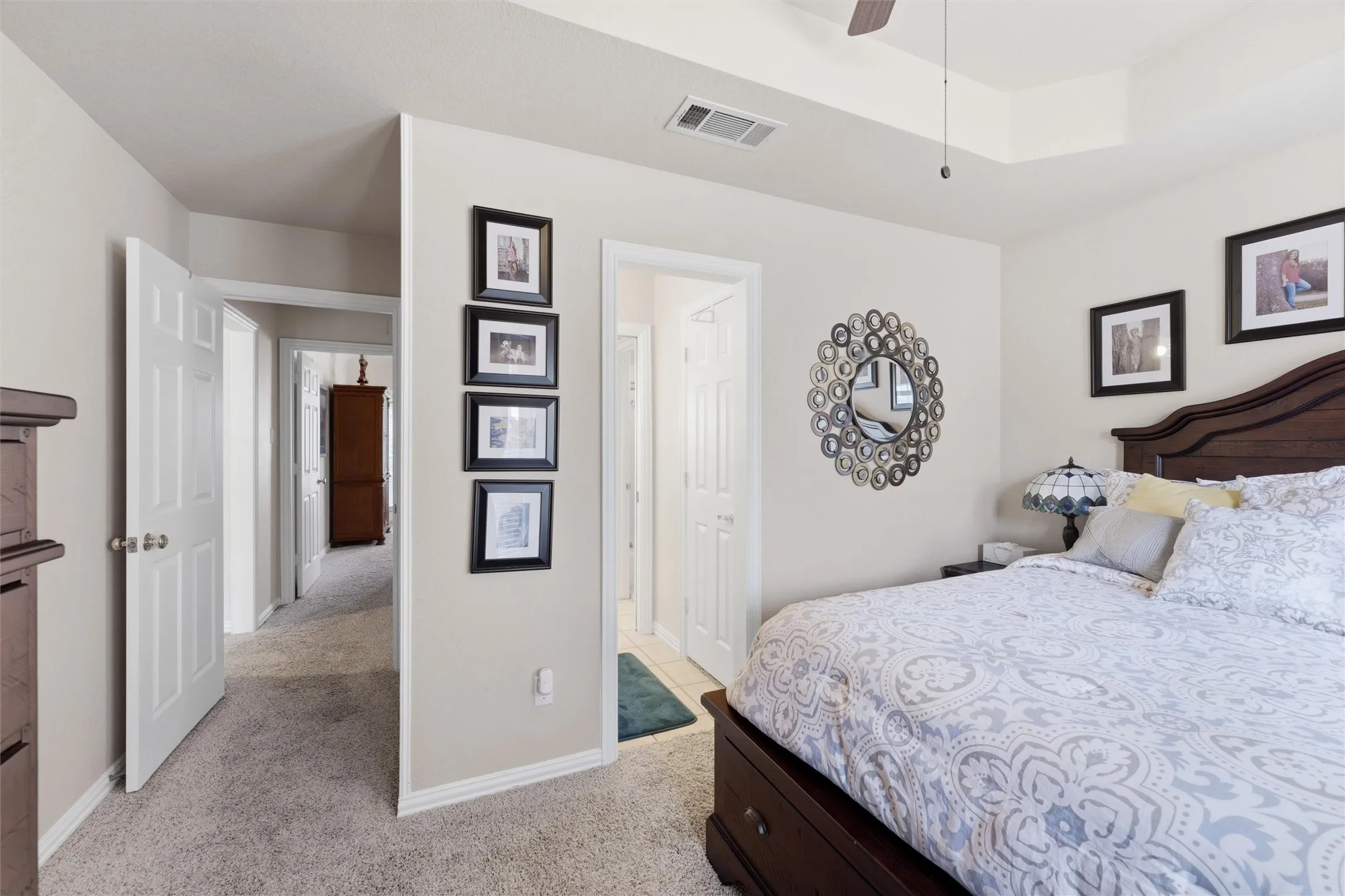 Bedroom with light colored carpet, a ceiling fan, and a raised ceiling