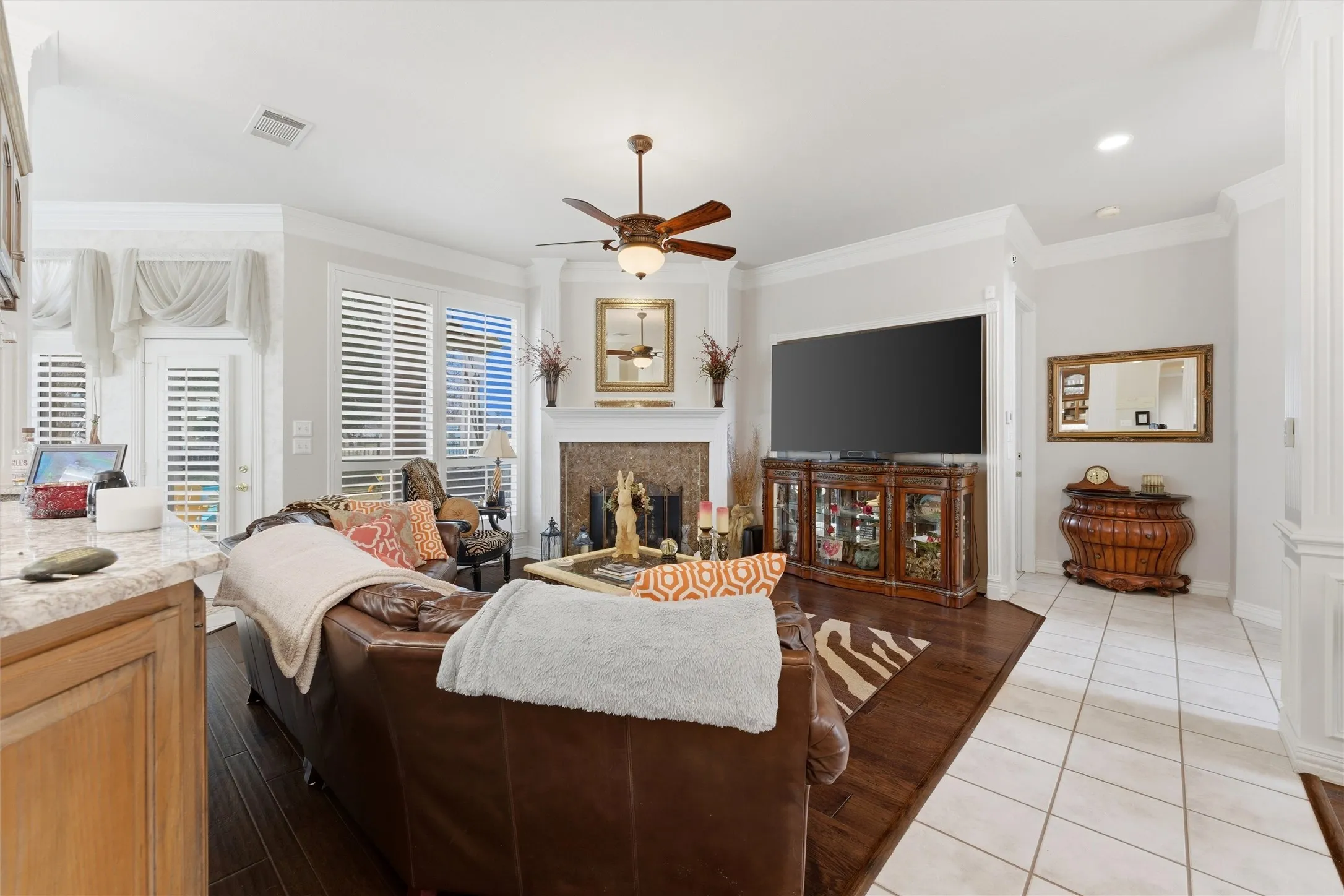 Living room with ceiling fan, ornamental molding, light tile patterned floors, and a premium fireplace