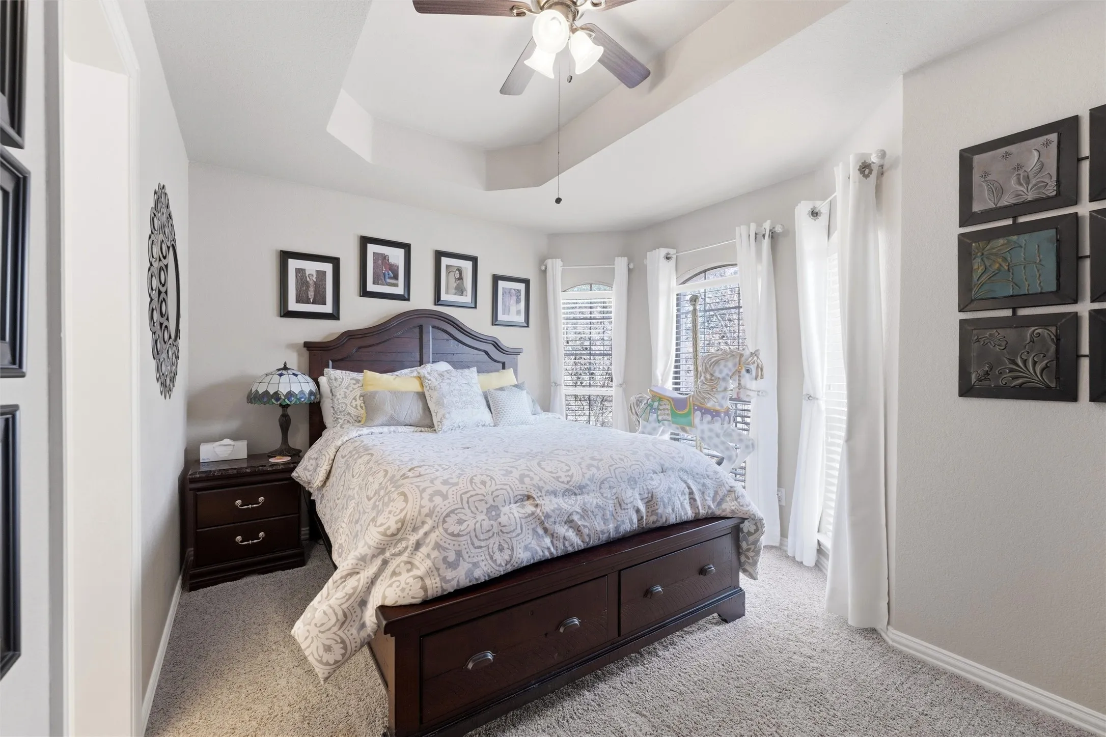 Bedroom featuring a raised ceiling, a ceiling fan, and light colored carpet