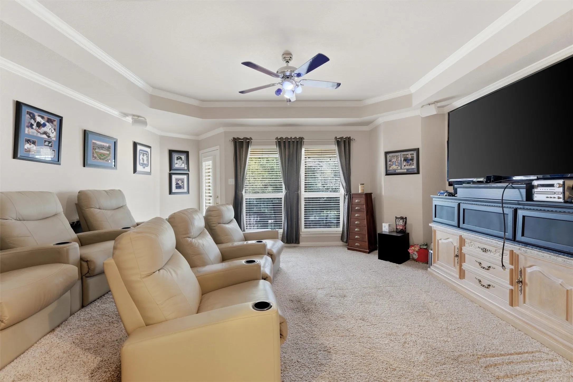 Living room with a ceiling fan, light carpet, ornamental molding, and a tray ceiling