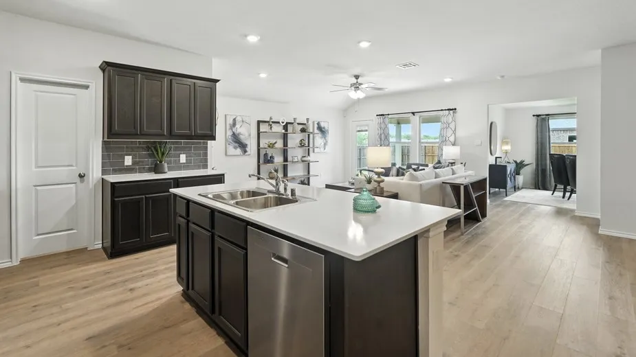 Kitchen featuring open floor plan, light countertops, dishwasher, backsplash, and a center island with sink