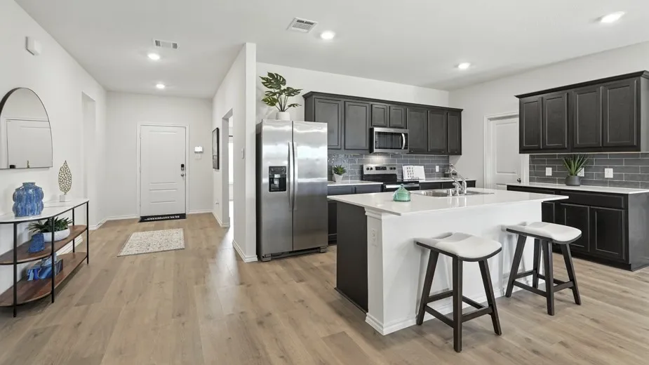 Kitchen featuring stainless steel appliances, a center island with sink, a breakfast bar, decorative backsplash, and light stone counters