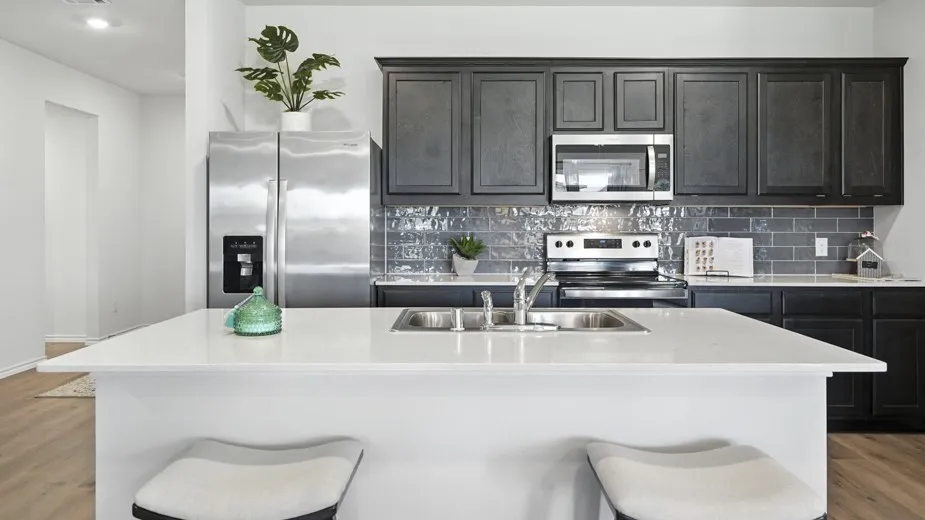 Kitchen featuring light wood-type flooring, a kitchen breakfast bar, stainless steel appliances, a center island with sink, and light stone counters