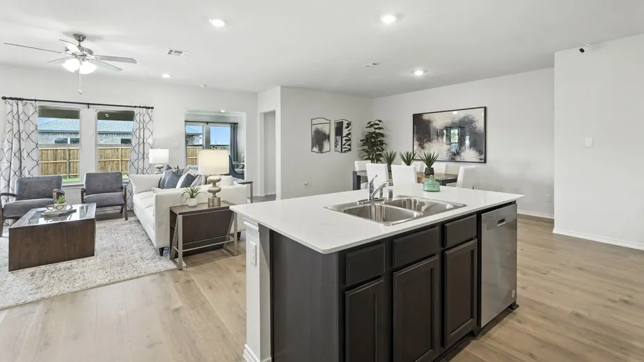 Kitchen featuring open floor plan, a center island with sink, ceiling fan, light wood-style flooring, and dishwasher