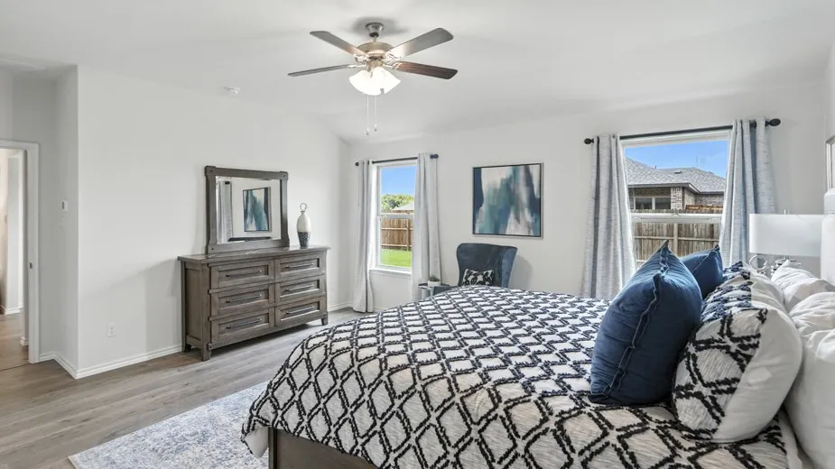 Bedroom with vaulted ceiling, light wood finished floors, and a ceiling fan