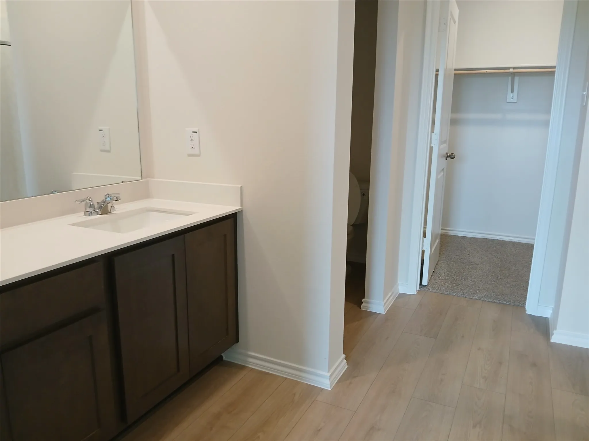 Bathroom vanity featuring a single basin, stainless steel faucet, and white countertop