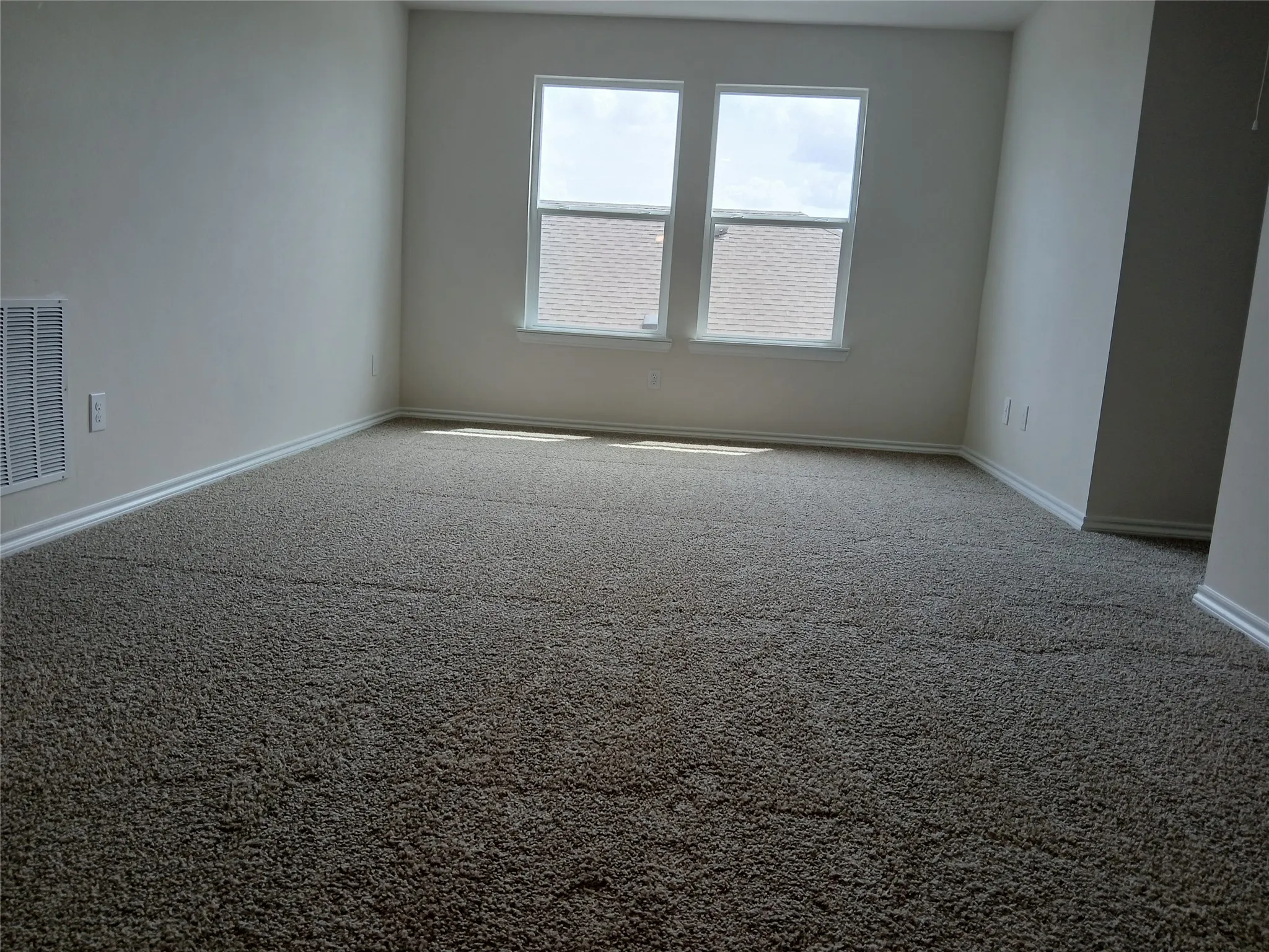 Spacious room featuring neutral carpeting and white baseboards