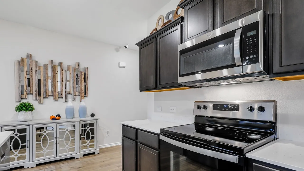 Modern kitchen featuring dark wood cabinetry, white countertops, and stainless steel appliances