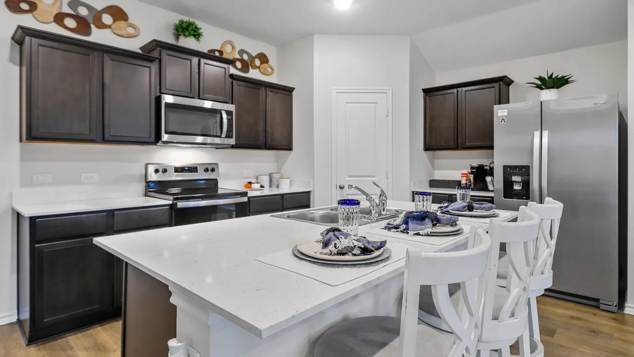 Kitchen featuring a central island with white countertop, dark wood-finish cabinetry, stainless steel appliances, and wood-finish flooring