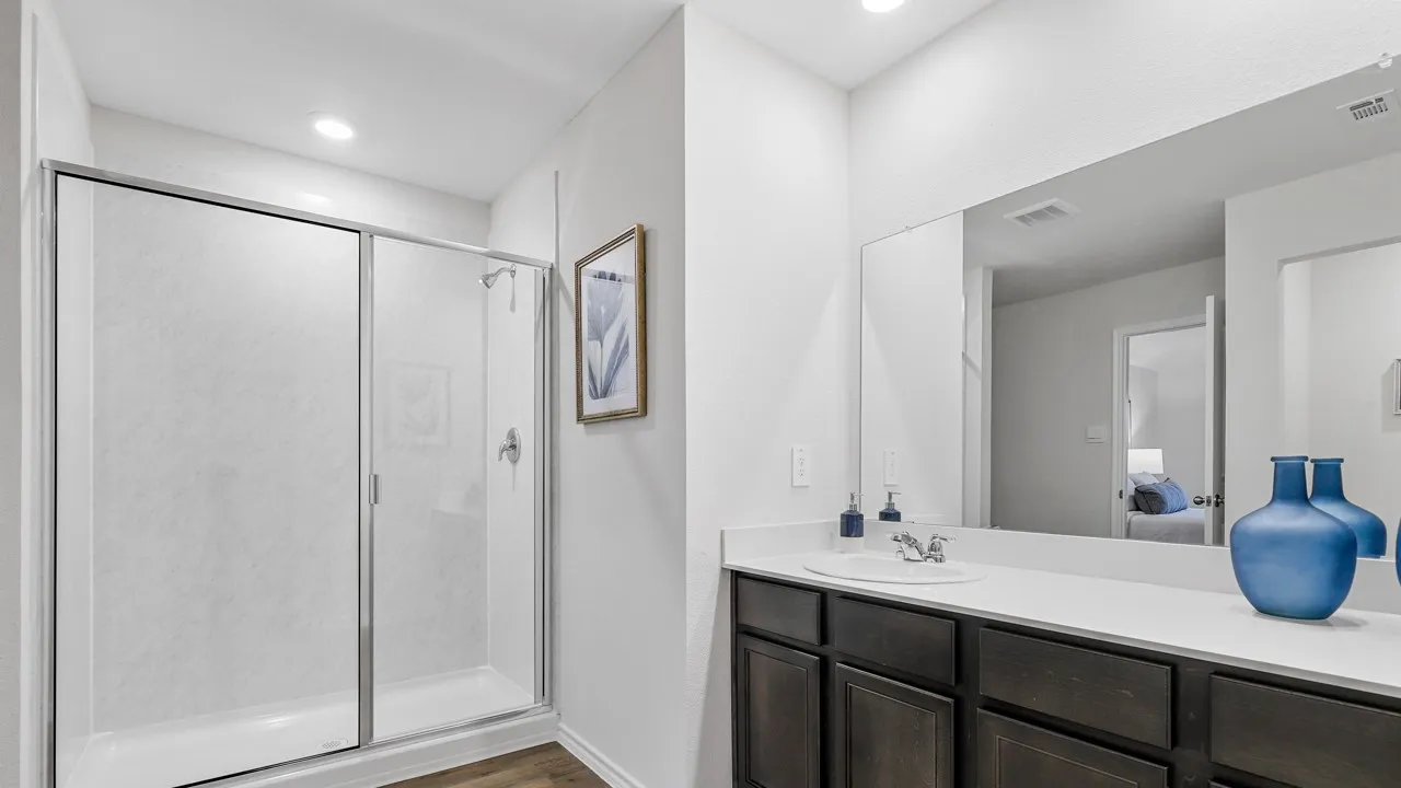 Bathroom featuring a standing shower with a clear glass enclosure, a single vanity with a white countertop, dark wood-finish cabinetry, and wood-finish flooring