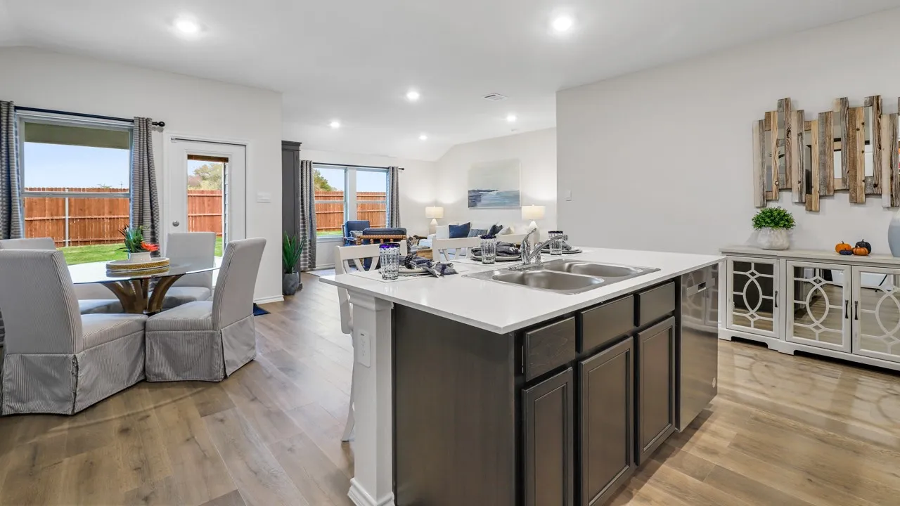 Kitchen island with a dual basin sink, white countertop, and dark cabinetry