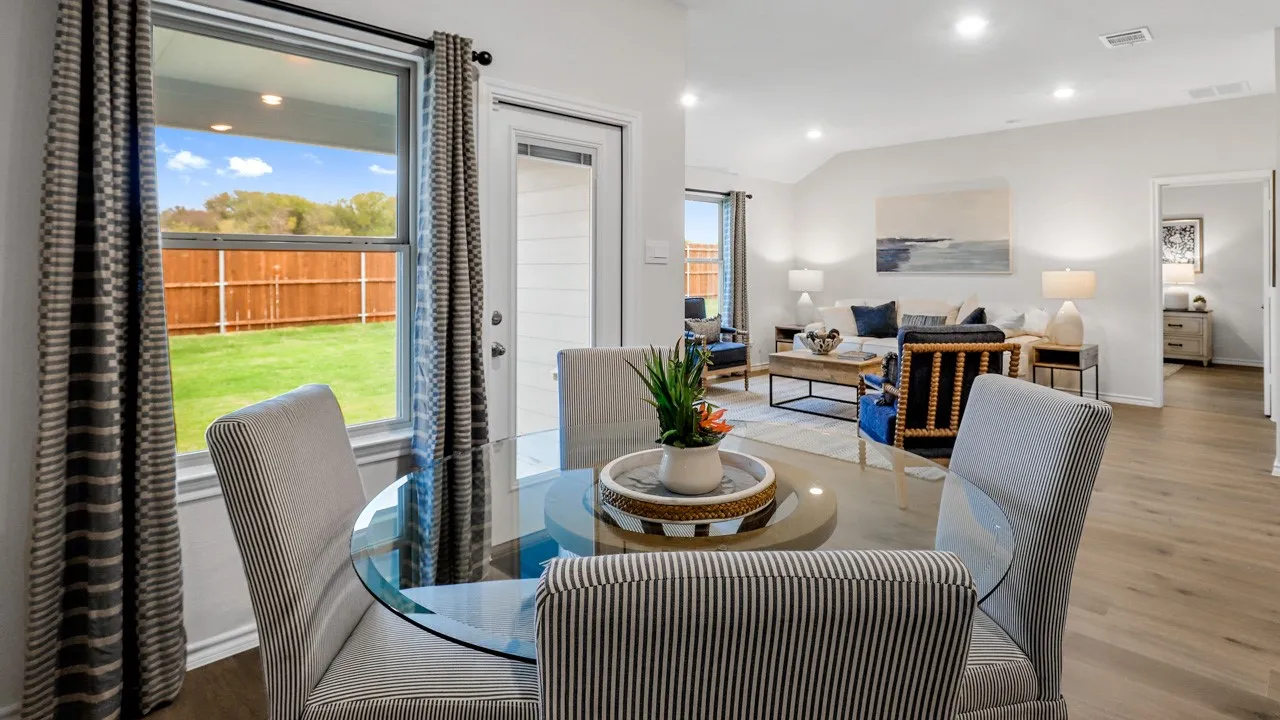 Dining area with a glass-top table, wood-finish flooring, recessed lighting, and a window overlooking a fenced backyard