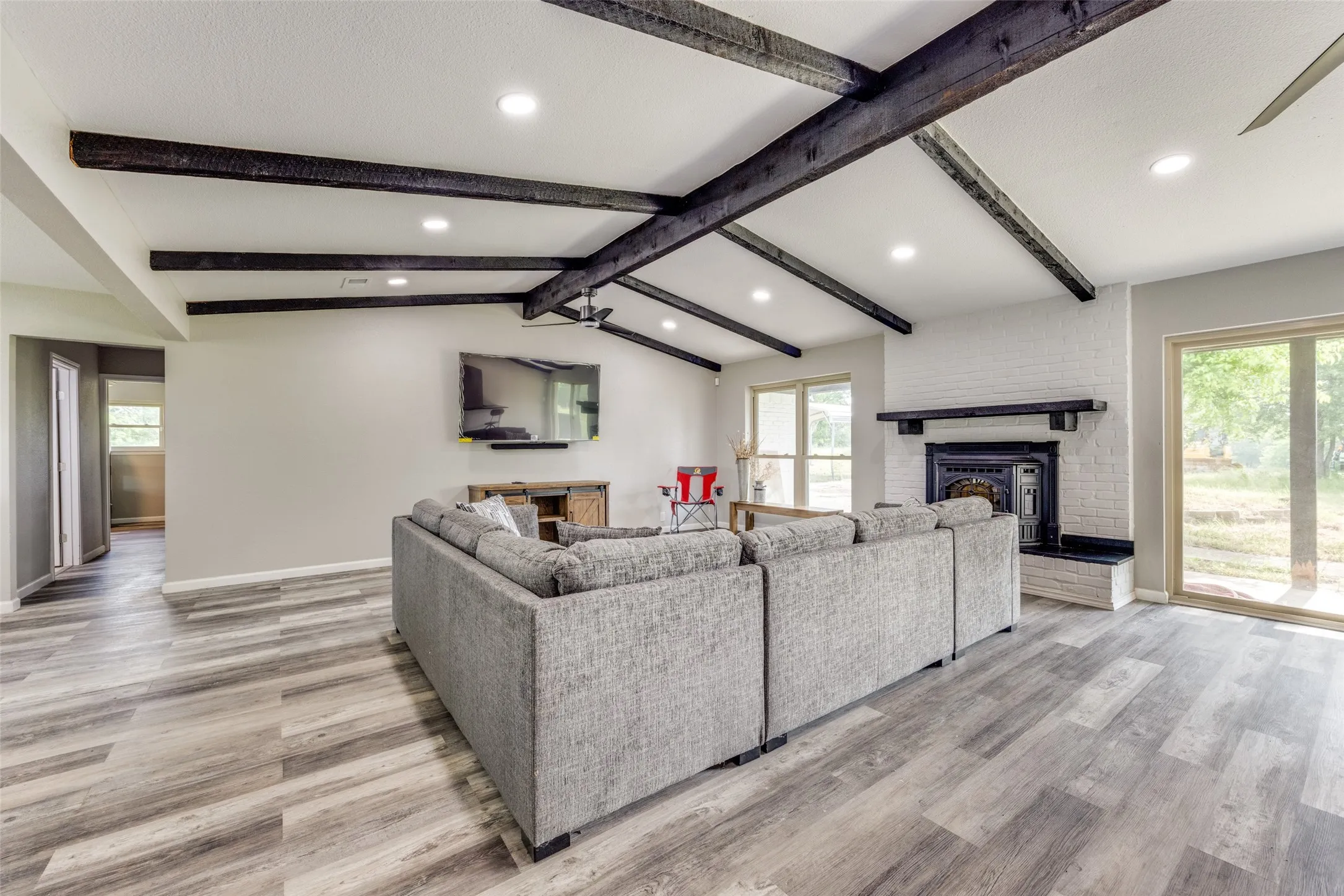 Living area featuring plenty of natural light, light wood-style floors, recessed lighting, and a brick fireplace