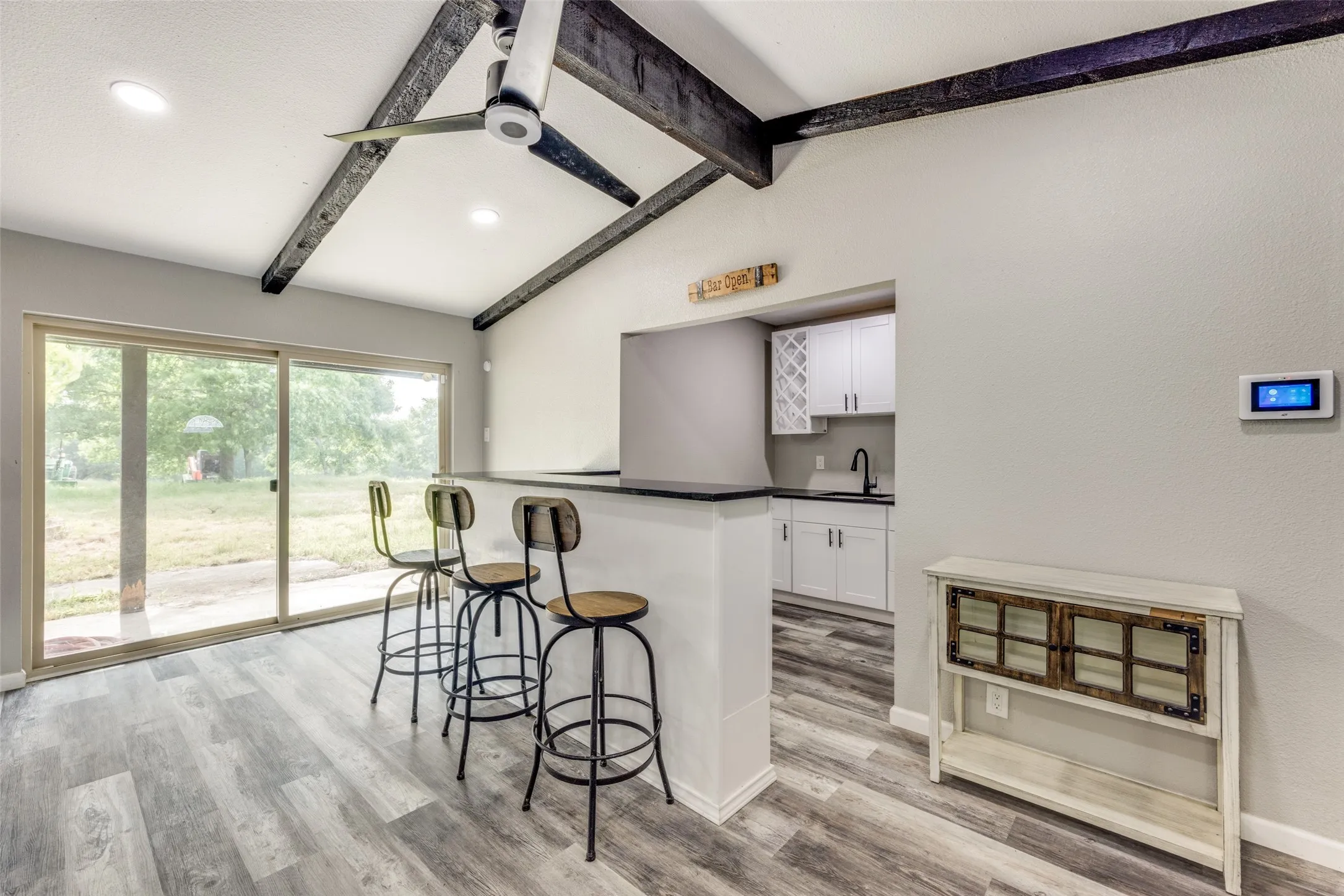 Kitchen with a kitchen breakfast bar, white cabinets, dark countertops, light wood-style floors, and a peninsula