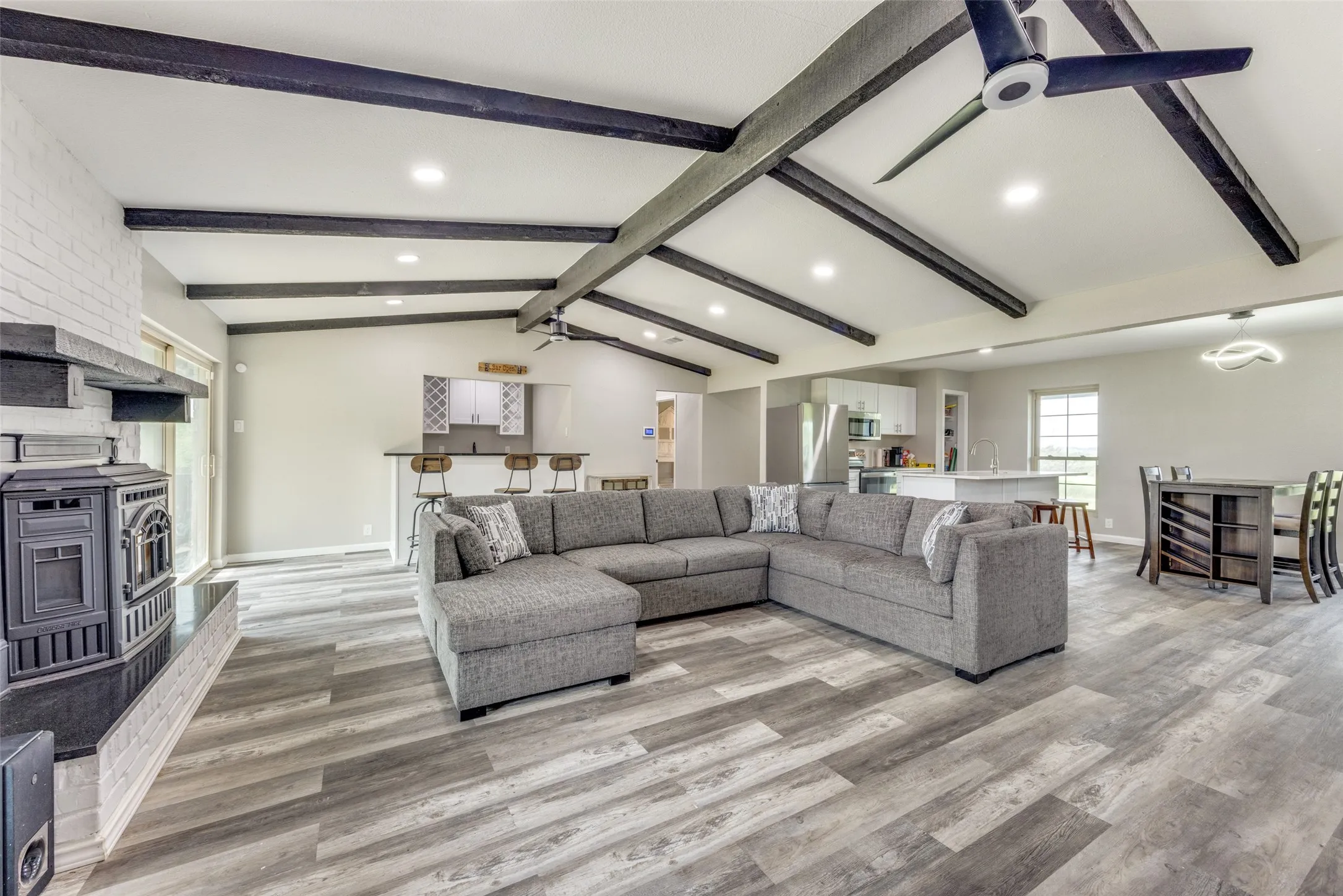 Living room with recessed lighting, light wood-style flooring, a wood stove, and a ceiling fan