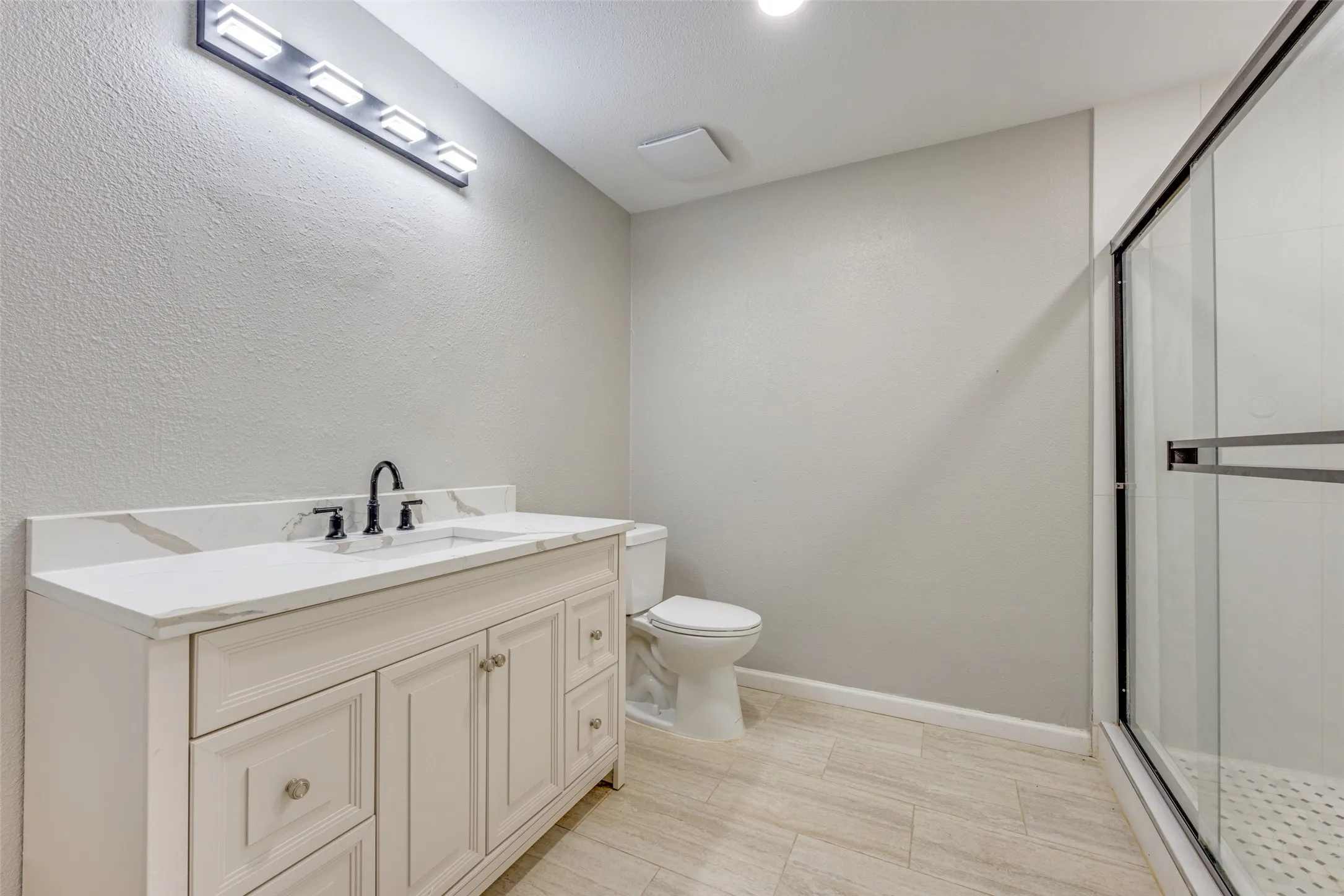 Bathroom featuring a stall shower, vanity, and a textured wall