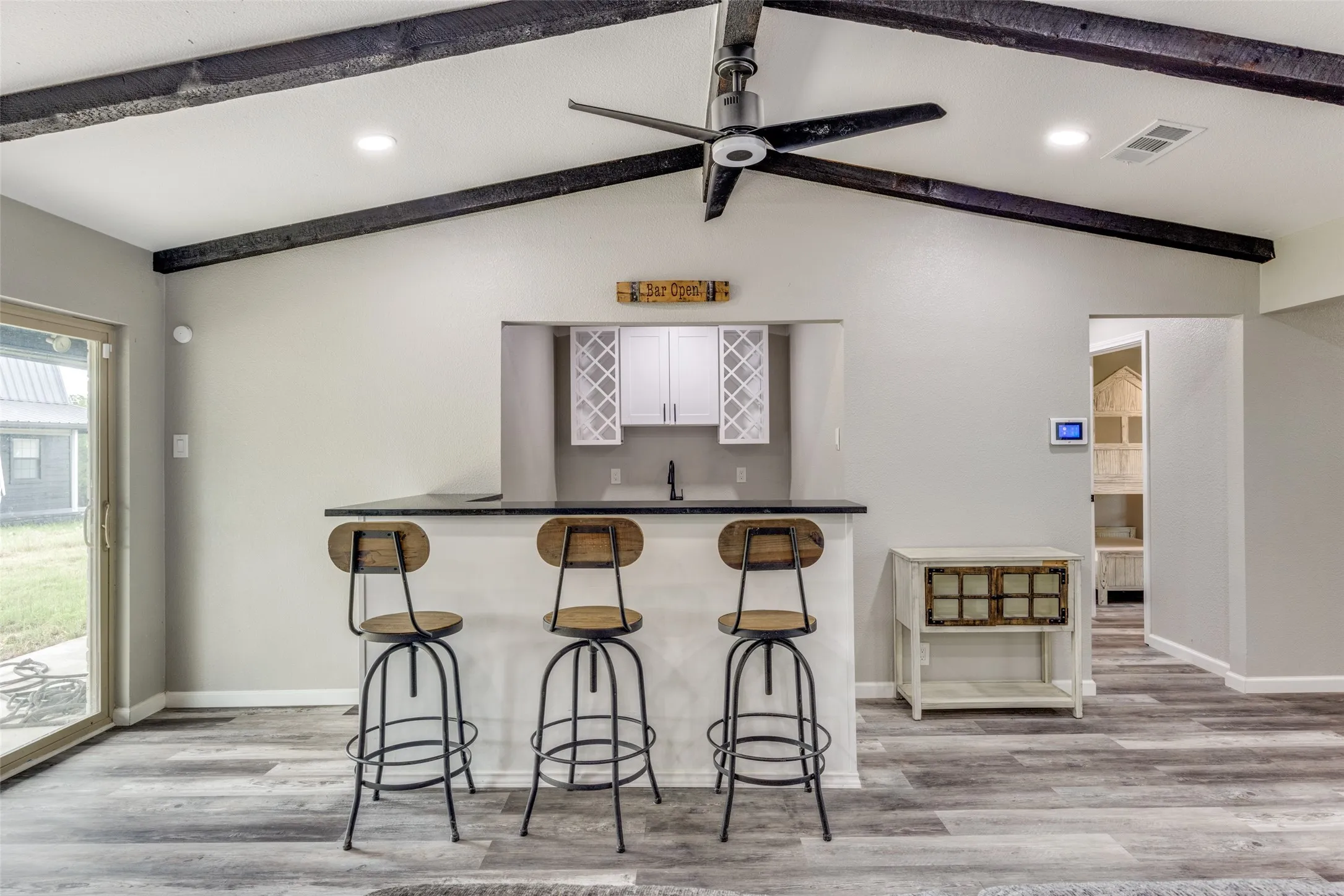 Indoor wet bar with light wood finished floors and a ceiling fan