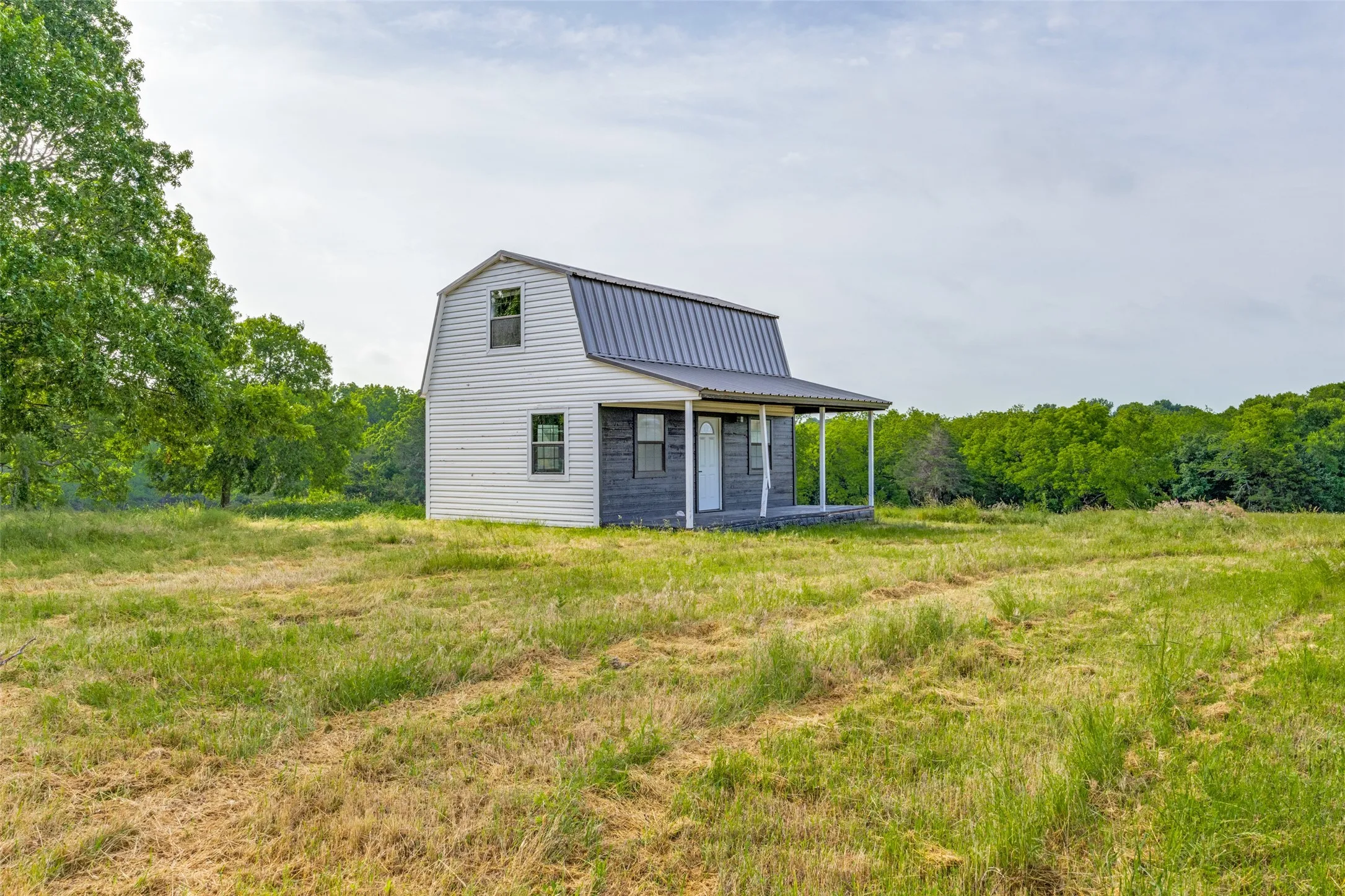 Rear view of house featuring a gambrel roof and a metal roof