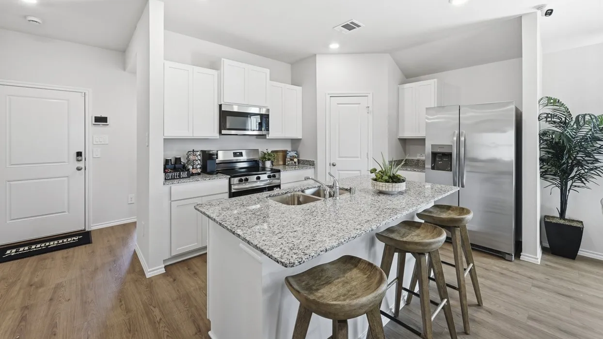 Modern kitchen featuring an island with granite countertops, stainless steel appliances, white cabinetry, and wood-finish flooring
