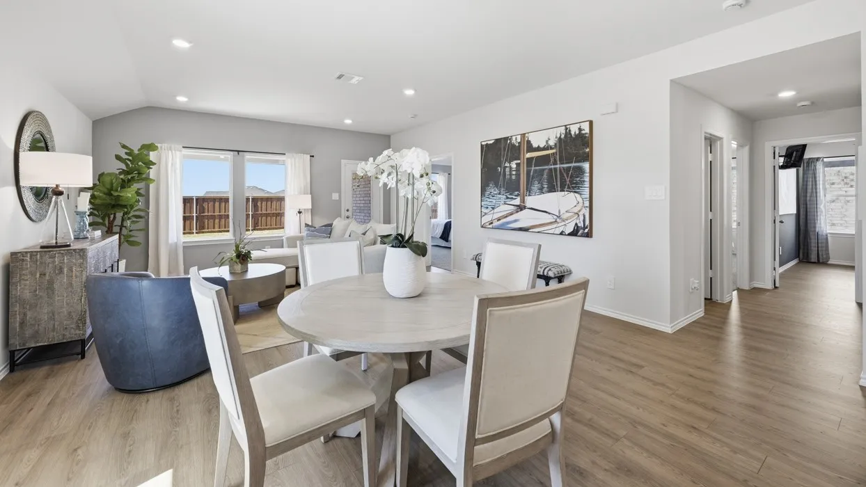 Open-concept living area featuring wood-finish flooring, vaulted ceilings, recessed lighting, and large windows