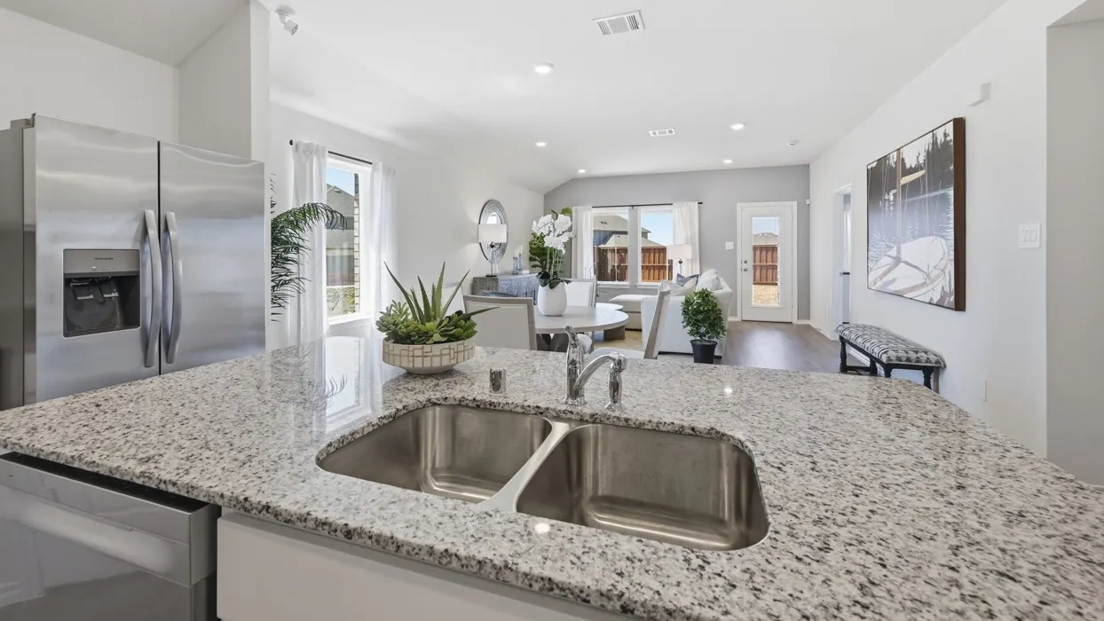 Open-concept living area featuring a kitchen island with dual stainless steel sink, granite-style countertop, and stainless steel appliances