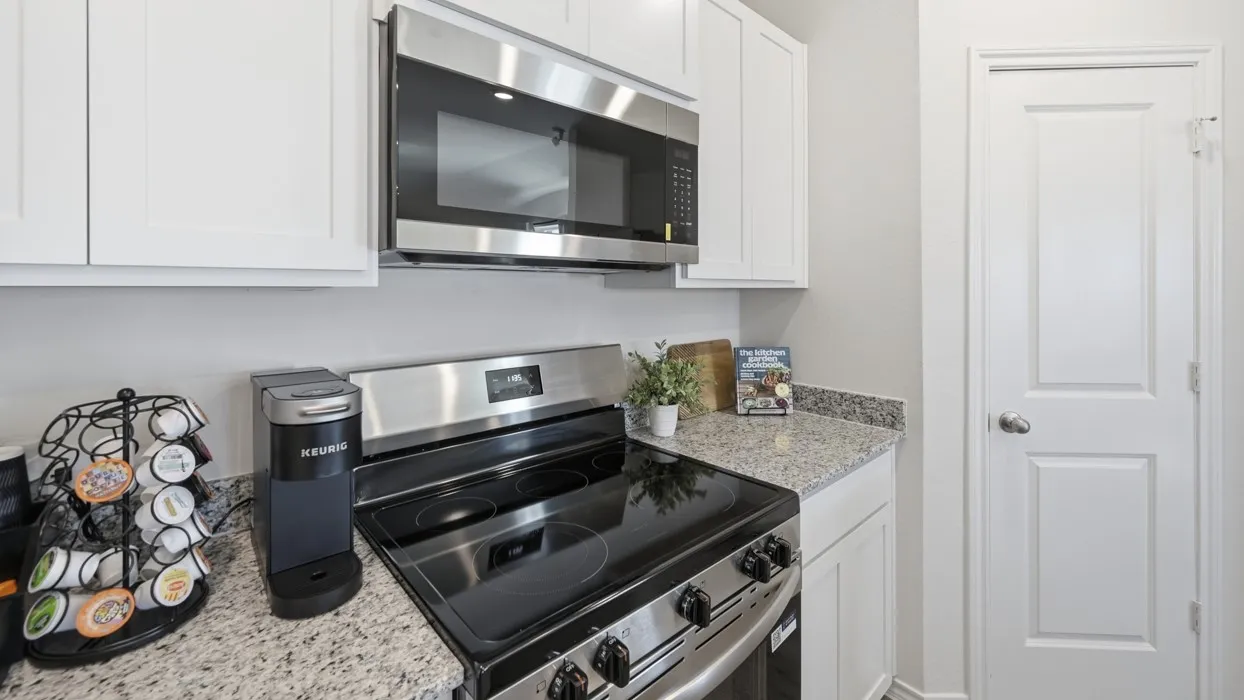 Kitchen featuring white shaker-style cabinetry, granite-finish countertops, stainless steel appliances, and a built-in microwave