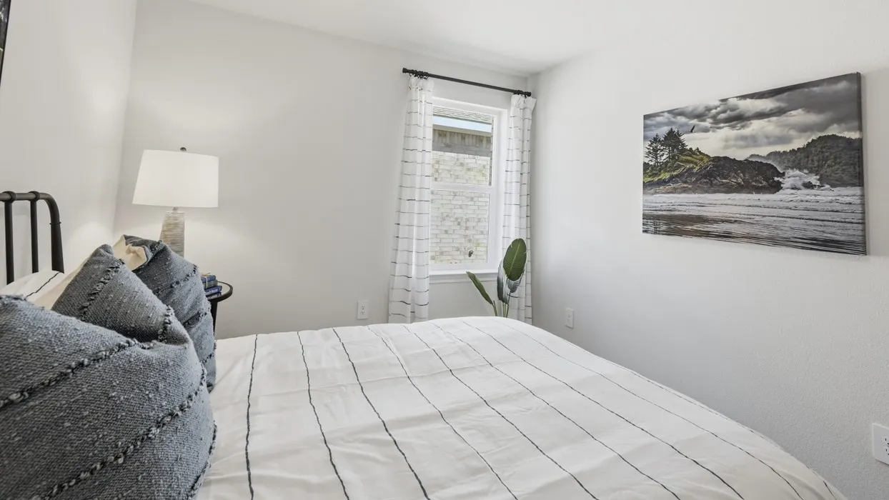 Bright bedroom featuring light-toned walls and a single window with dark curtain rod