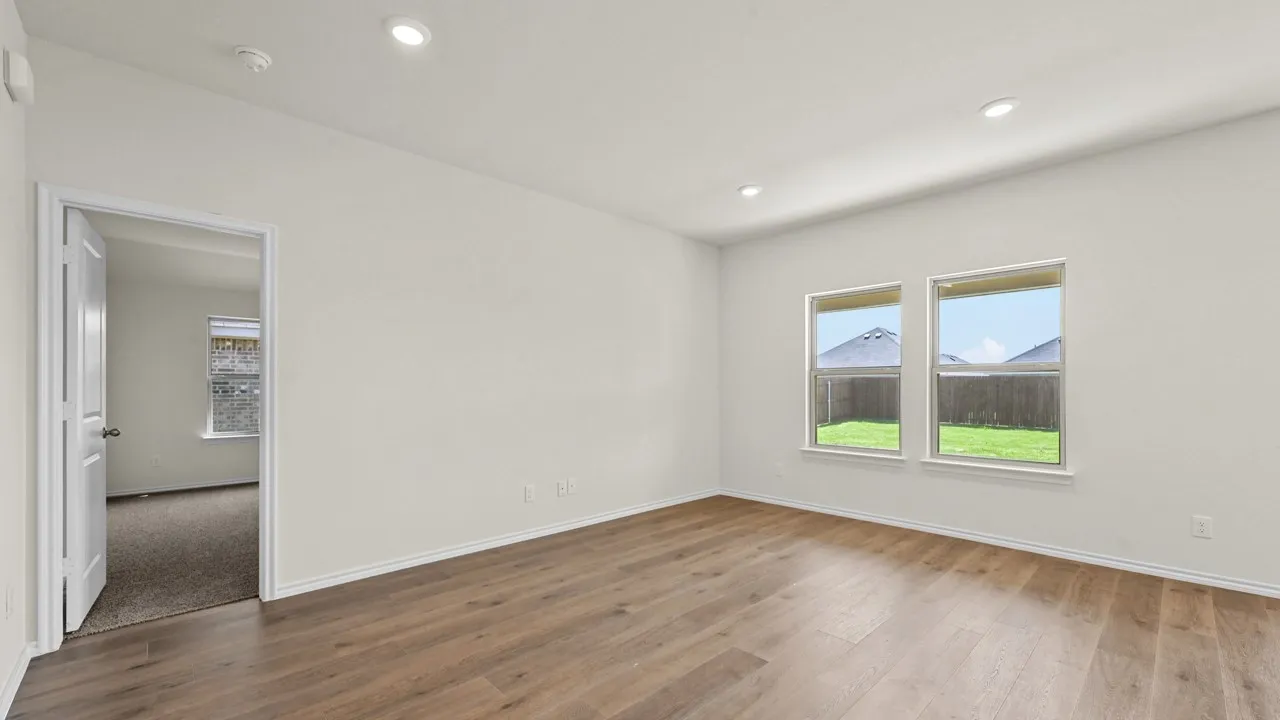 Spacious room featuring wood-finish flooring, recessed lighting, and two windows providing exterior views