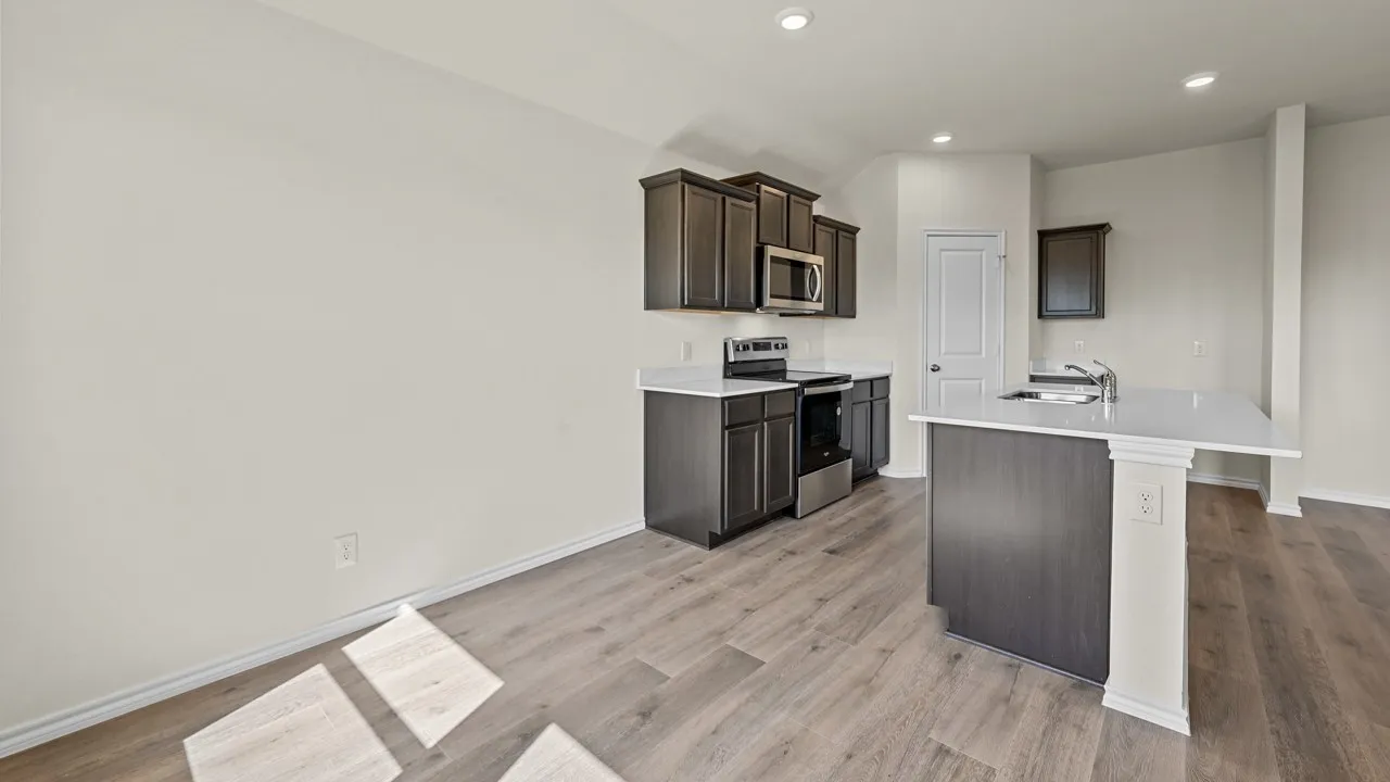 Contemporary kitchen featuring dark wood cabinetry, stainless steel appliances, light-toned countertops, and wood-finish flooring