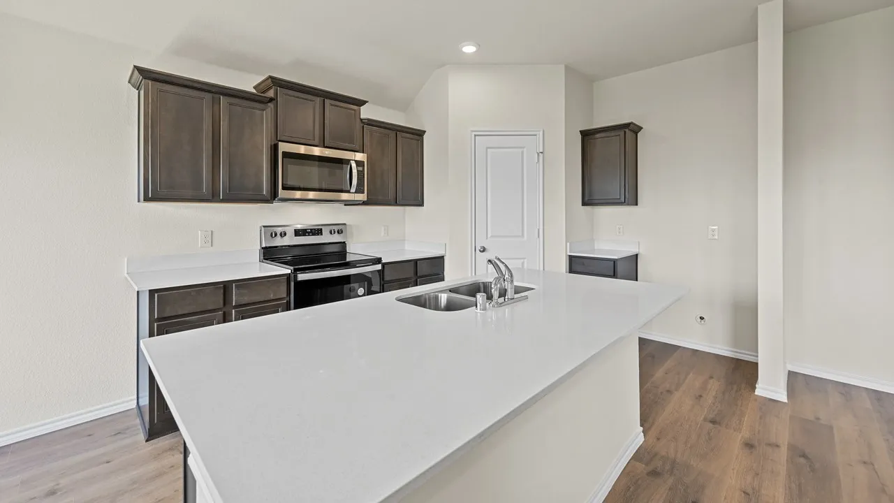 Kitchen featuring an expansive island with an integrated sink, dark wood-finish cabinetry, stainless steel appliances, white countertops, and wood-finish flooring