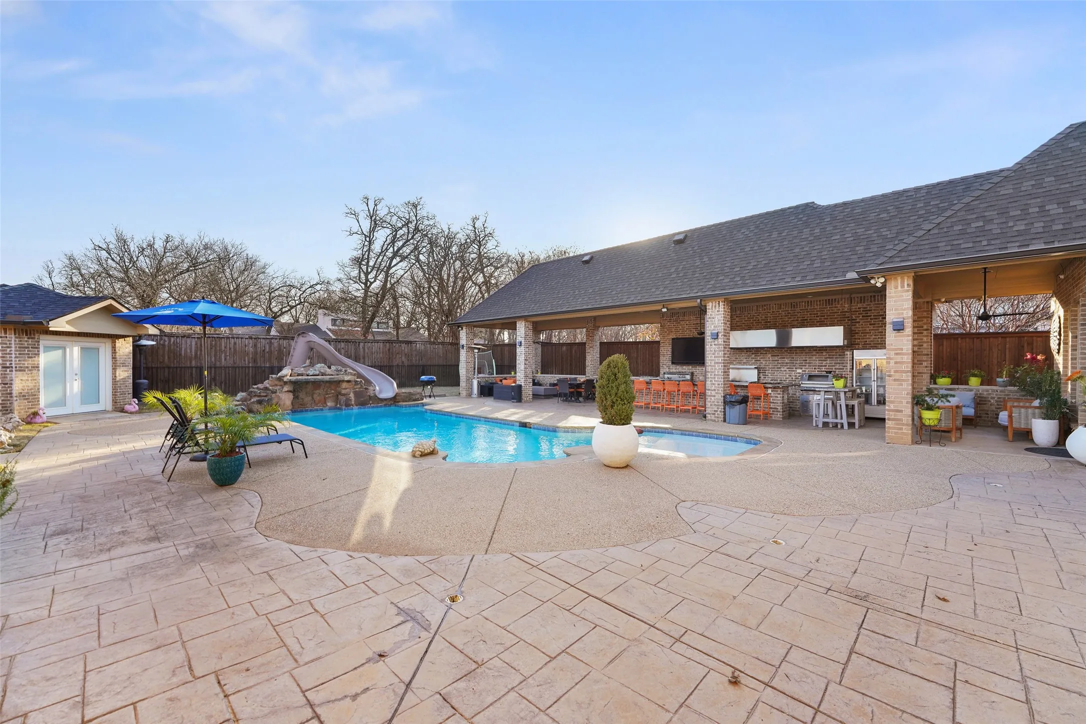 View of swimming pool with a water slide, patio surround, a fenced backyard, area for grilling, and french doors