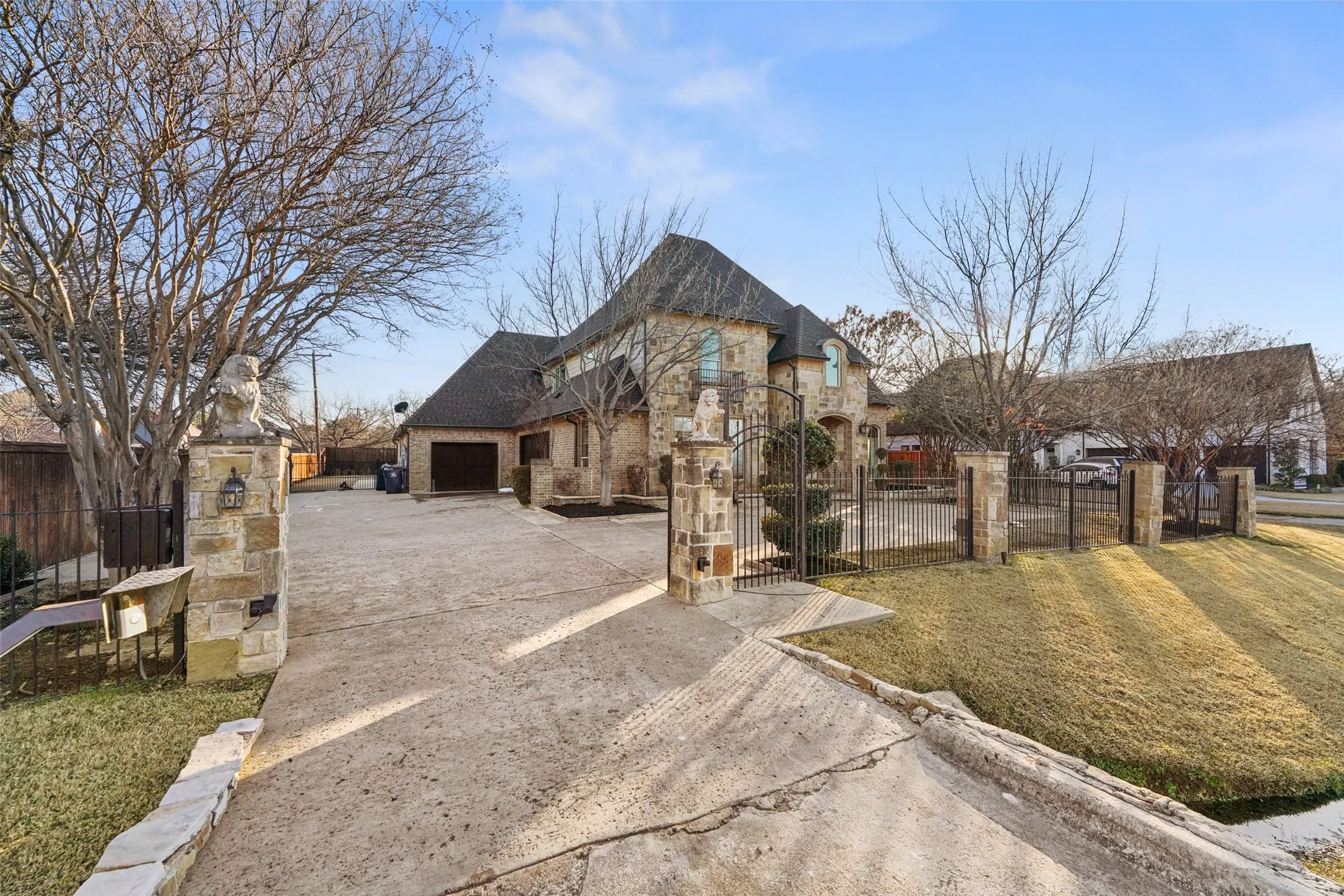 View of front of home with driveway, a fenced front yard, stone siding, a gate, and an attached garage