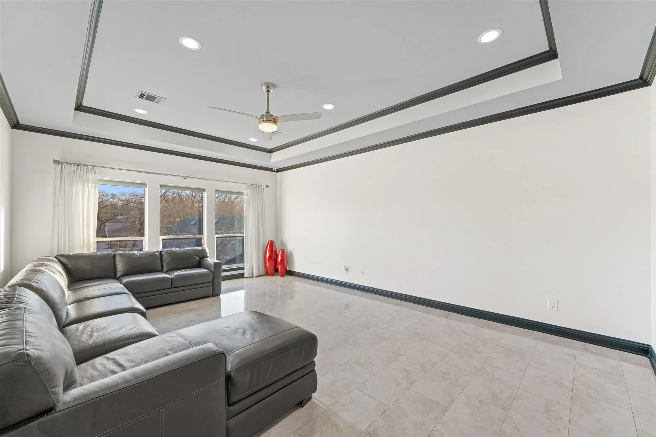 Living room with ceiling fan, a raised ceiling, crown molding, and recessed lighting