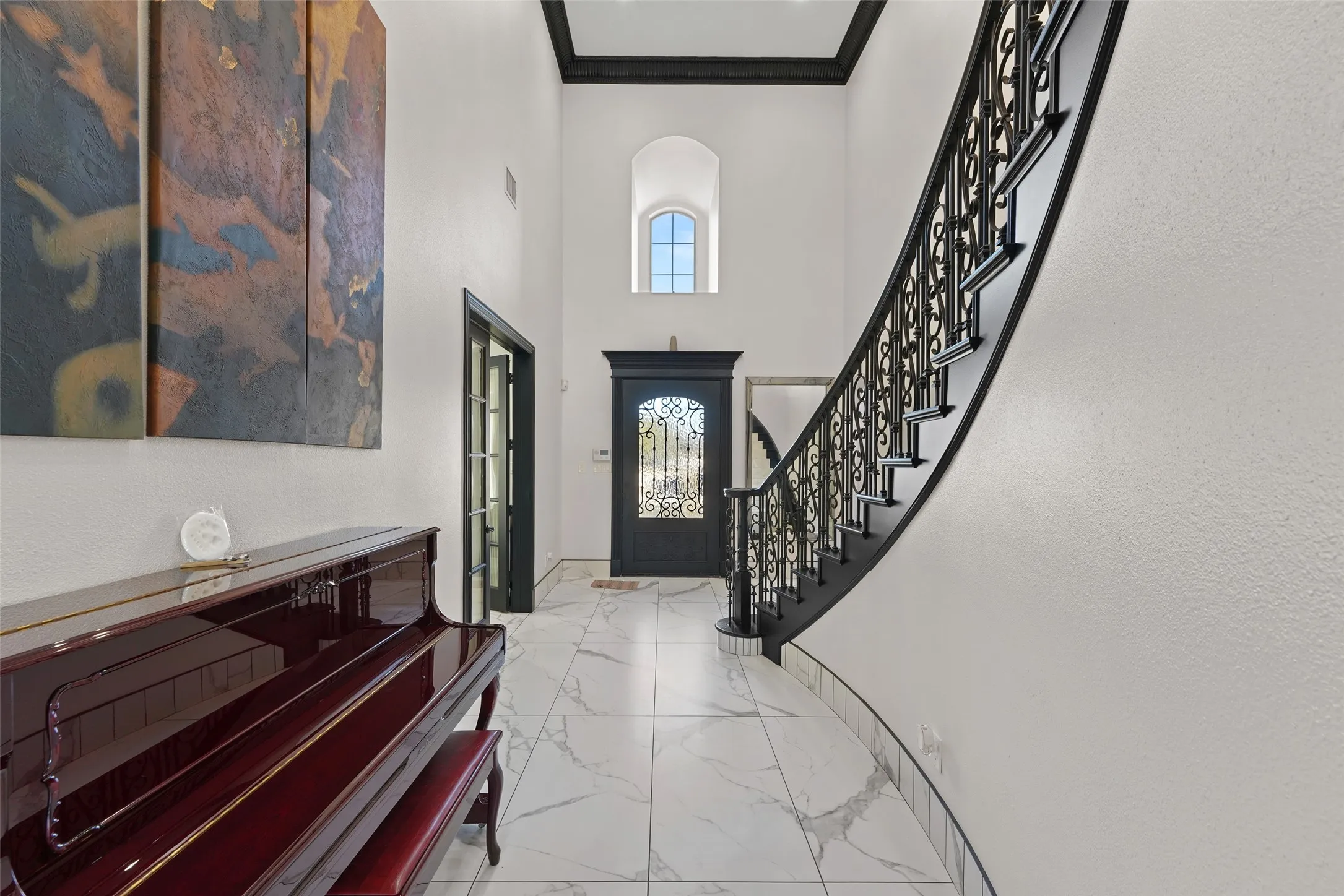 Foyer featuring light marble finish flooring, a high ceiling, and ornamental molding