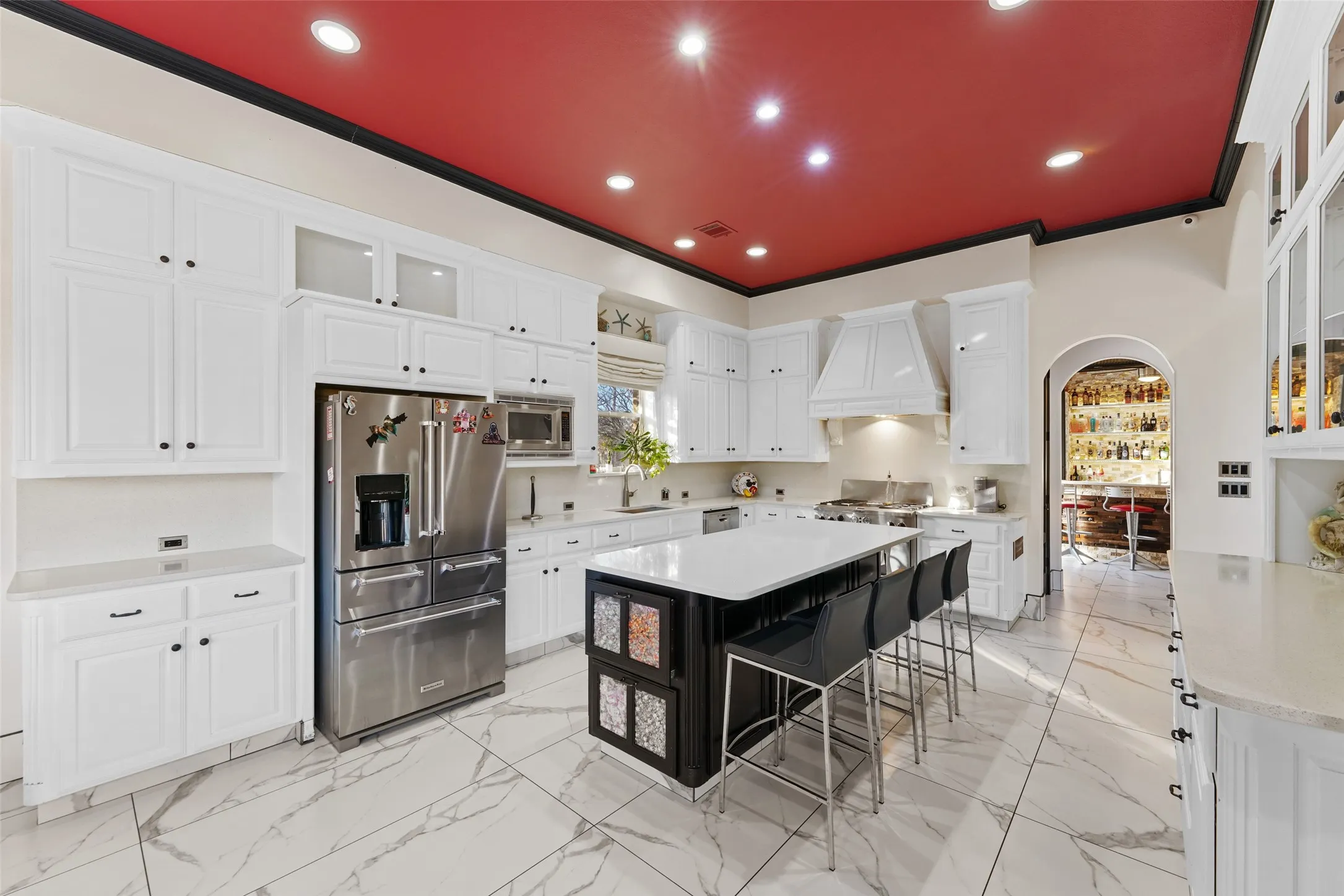 Kitchen with glass insert cabinets, stainless steel appliances, a breakfast bar, a kitchen island, and ornamental molding