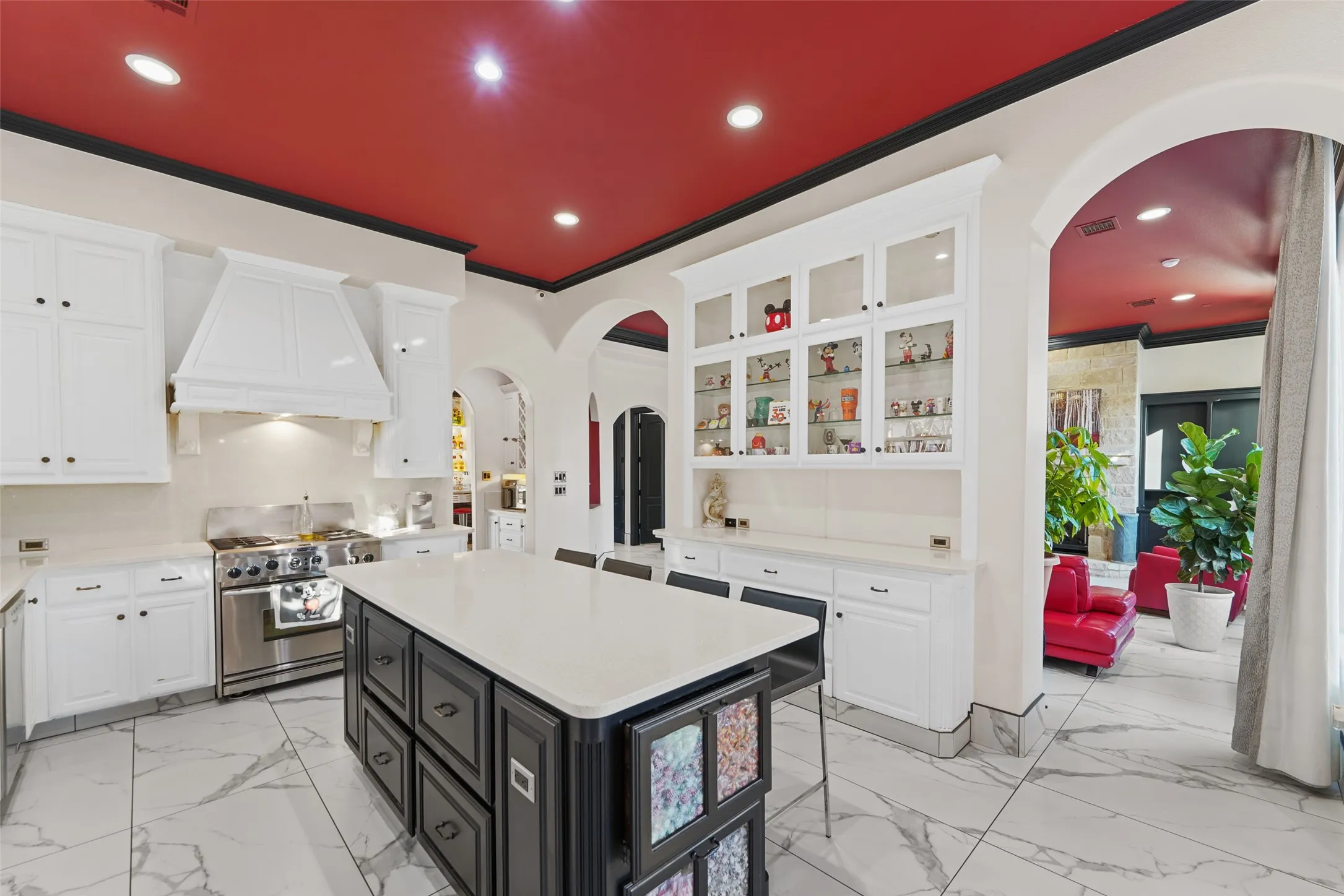 Kitchen featuring arched walkways, glass fronted cabinets, a kitchen island, high end stainless steel range oven, and light stone counters