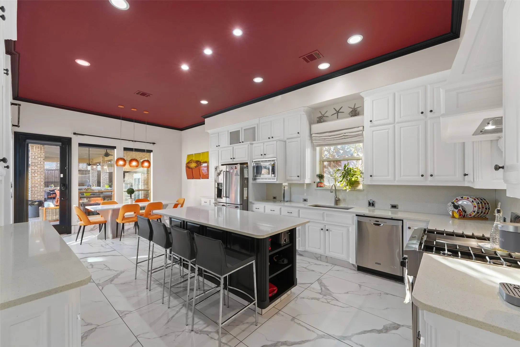 Kitchen featuring light stone countertops, stainless steel appliances, a kitchen bar, light marble finish floors, and a center island