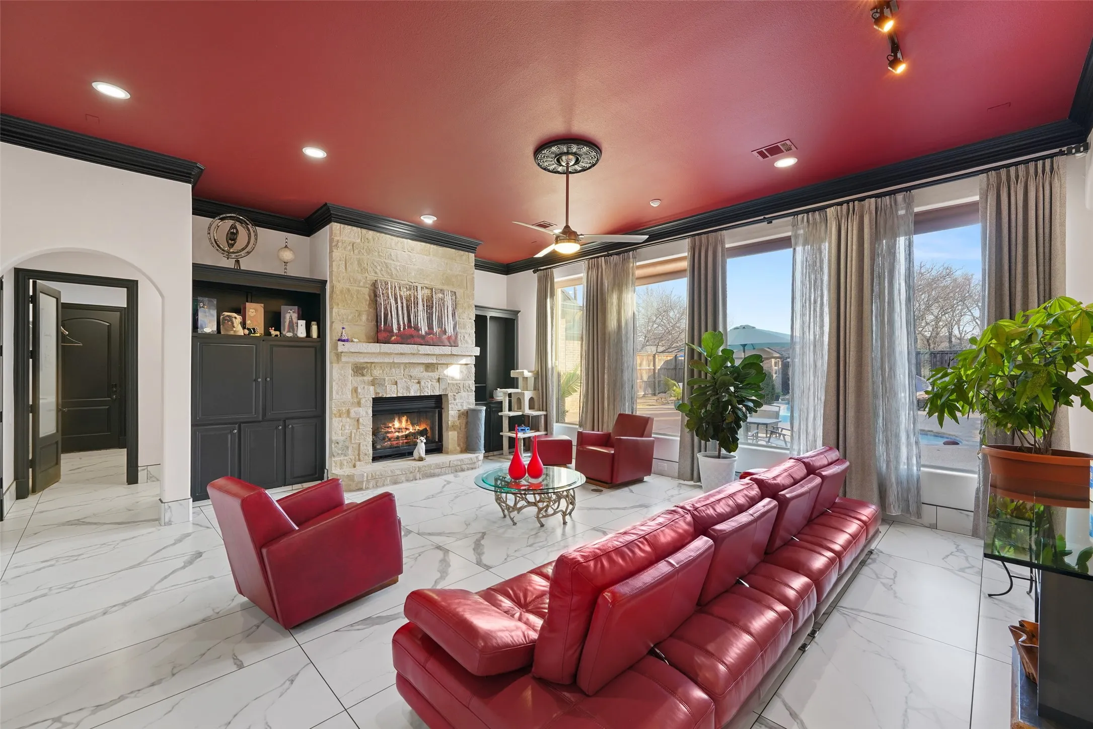 Living room with ceiling fan, crown molding, a fireplace, arched walkways, and recessed lighting