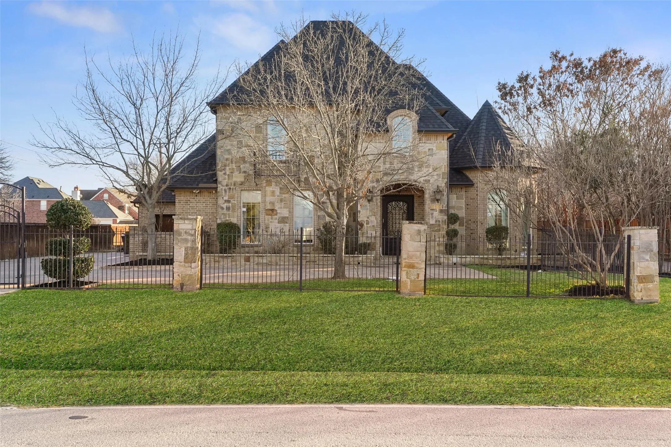 French country style house with stone siding, a fenced front yard, and brick siding