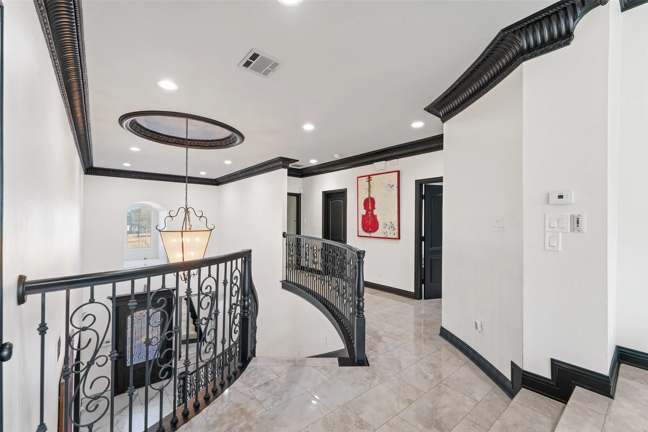 Hallway with an upstairs landing, suspended lighting, and ornamental molding