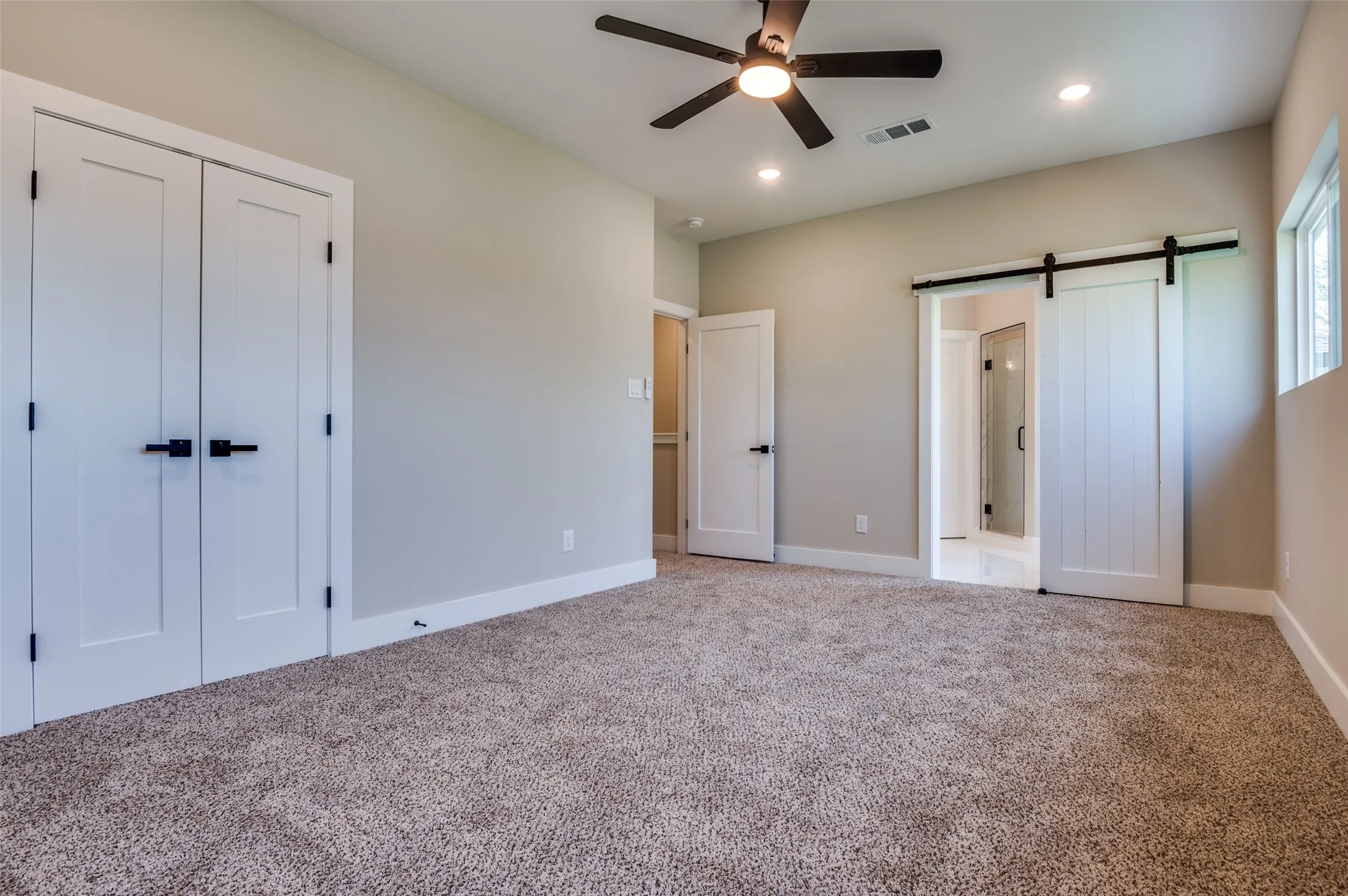 Primary bedroom has barn door entrance to bath area